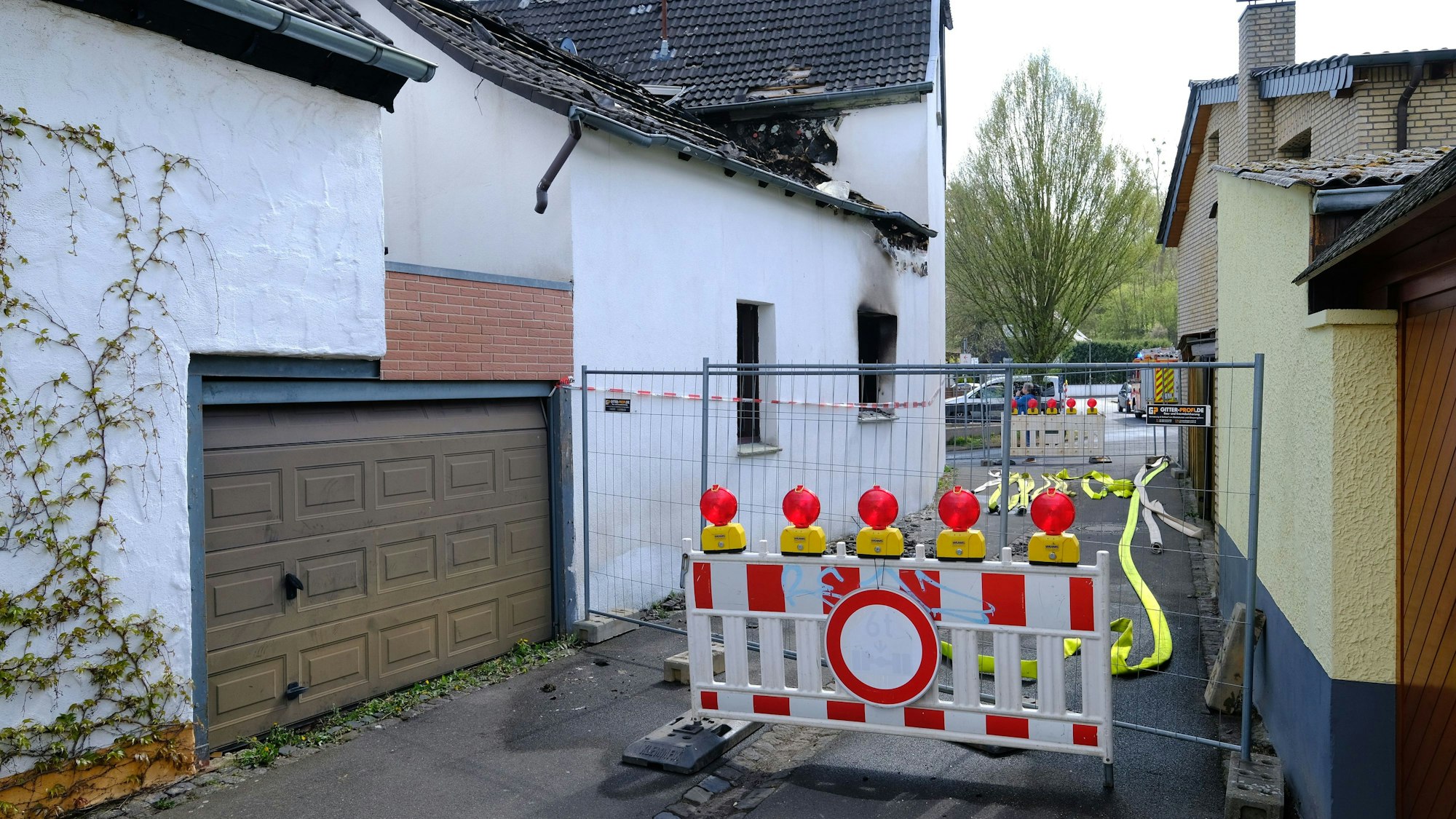 Die Gasse, an der das ausgebrannte Haus liegt, ist mit einem Bauzaun und einer Absperrbake abgesperrt.