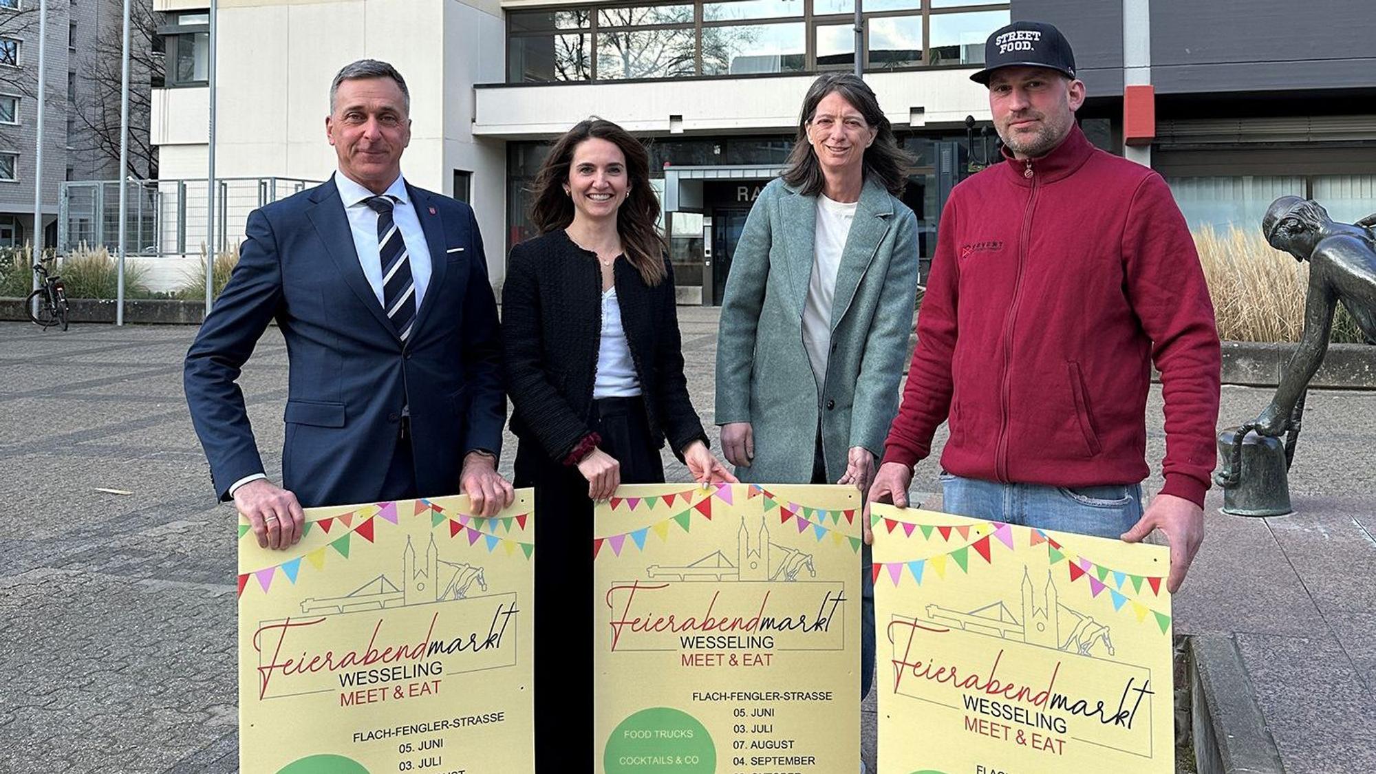 Zwei Frauen und zwei Männer halten Plakate.