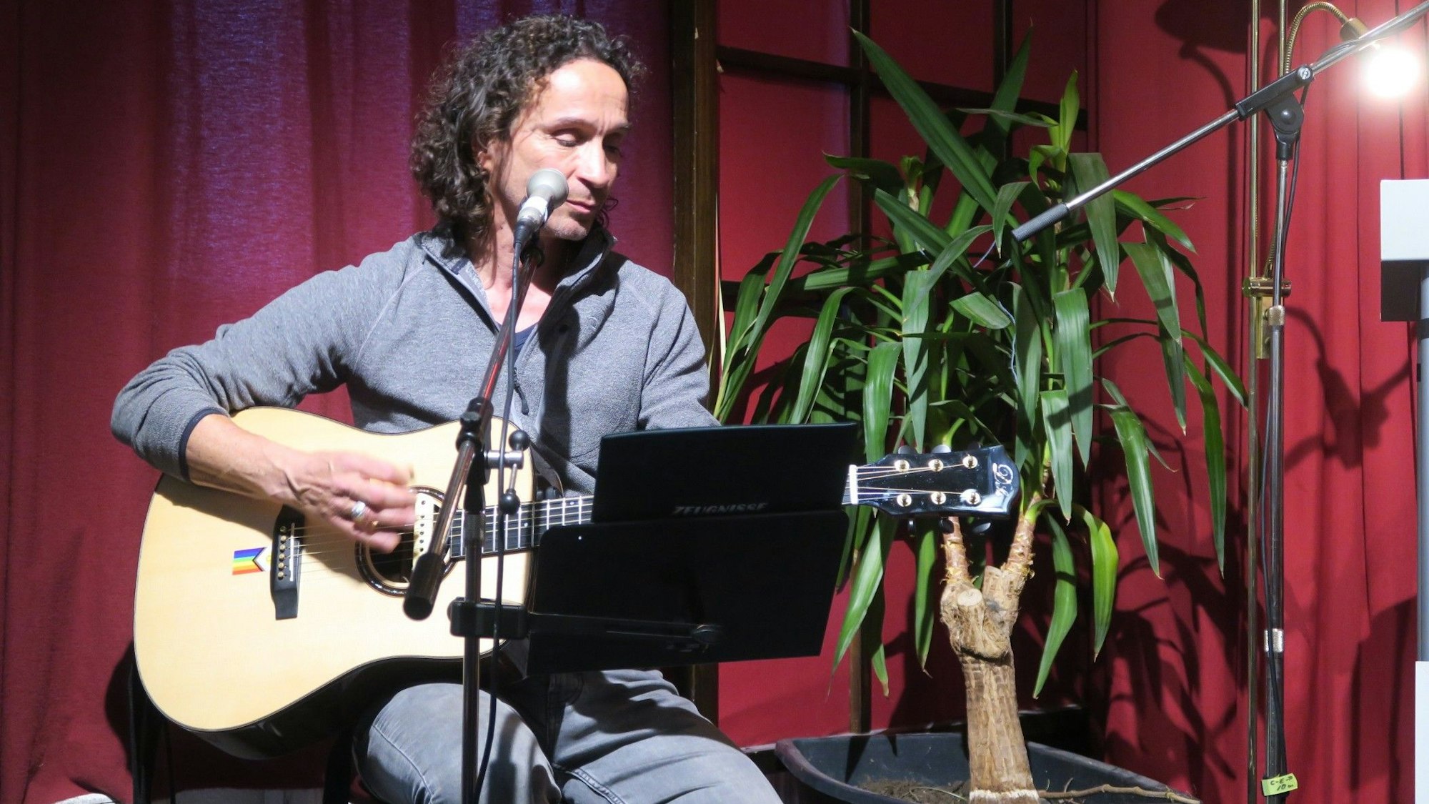 Ein Mann mit halblangem lockigen Haar spielt Gitarre.