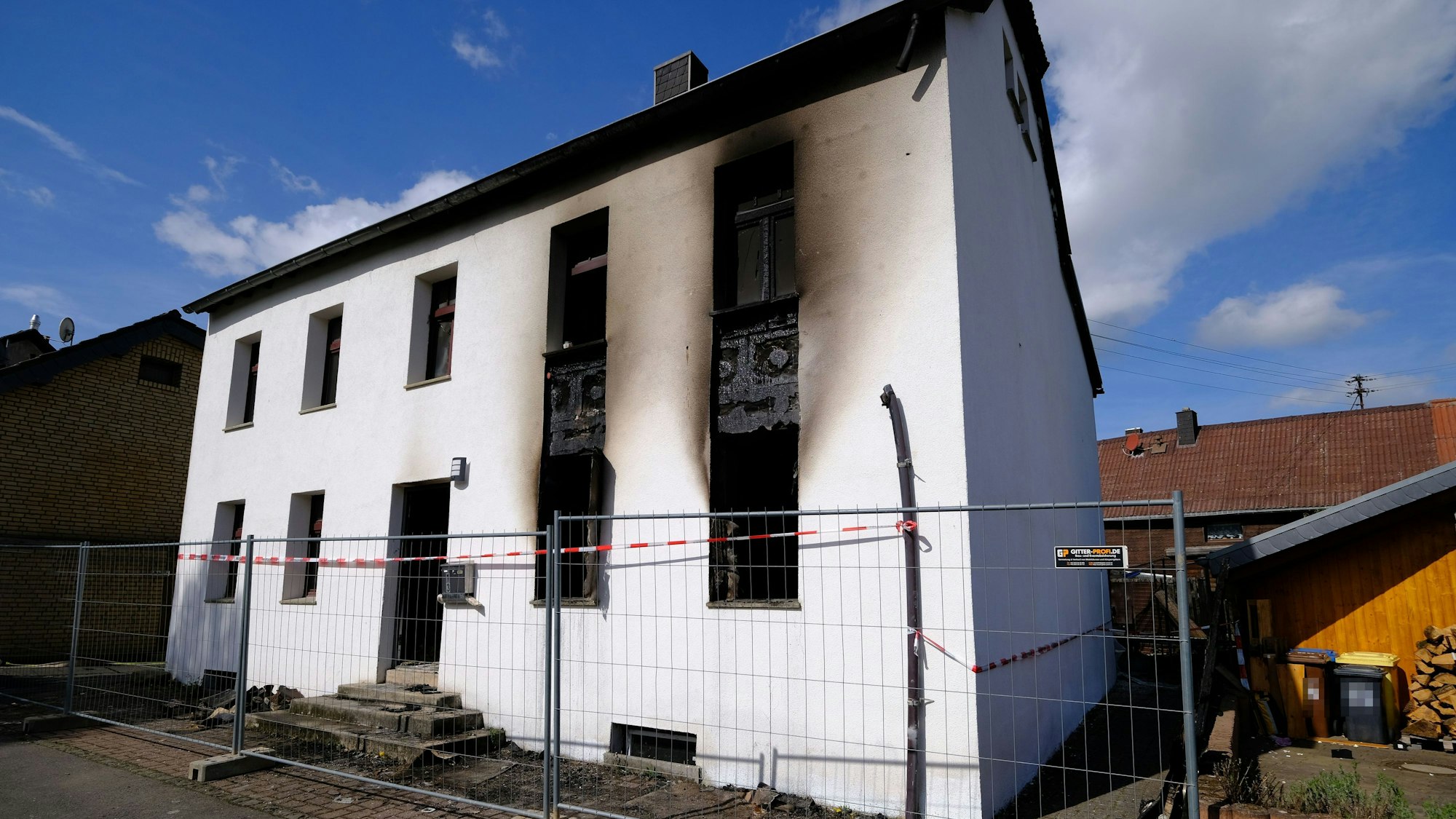 Das Bild zeigt das Gebäude mit rußgeschwärzter Fassade am Morgen nach dem Brand.