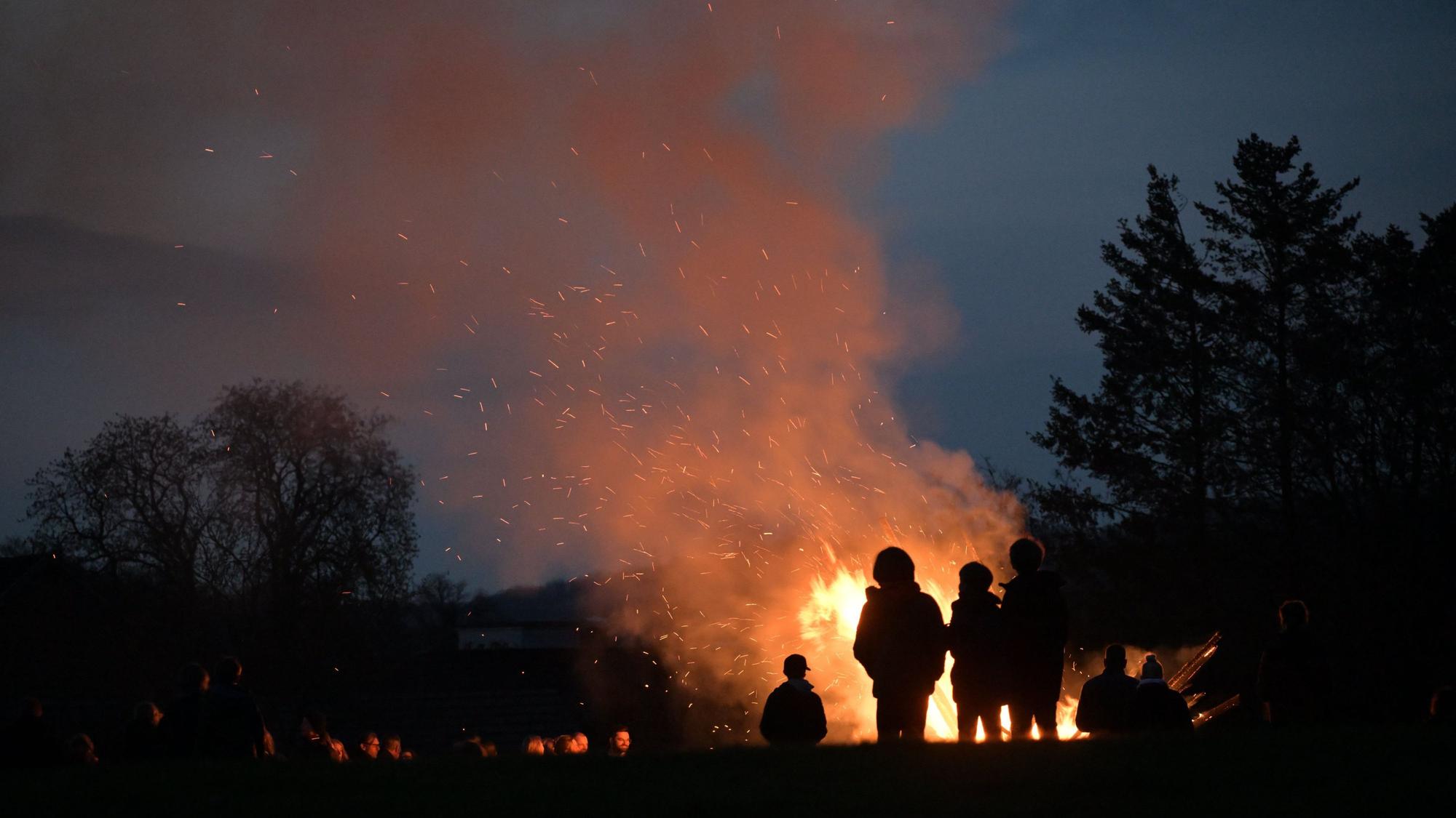 Bei Nacht steht eine Gruppe Menschen vor dem Osterfeuer auf dem Hofferhof in Hoffnungsthal.