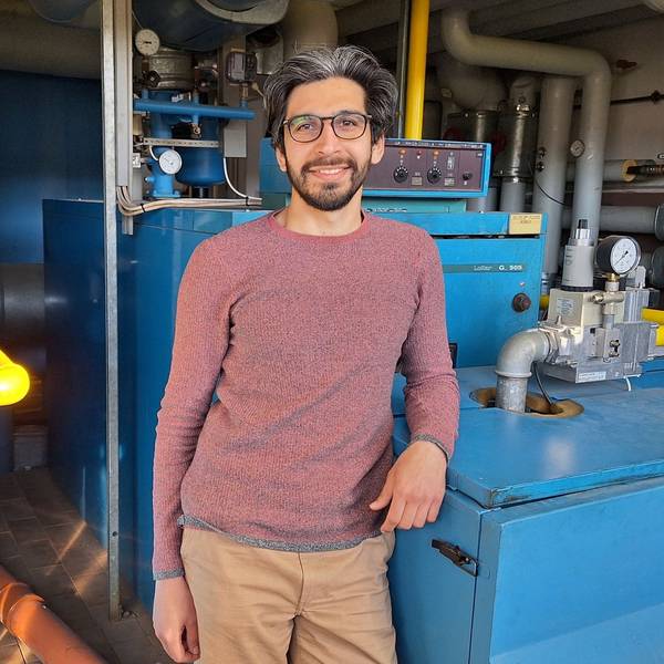 Der Energiemanager Nima Haghighatian lehnt sich mit dem Ellbogen an die Heizungsanlage der Grundschule in Dahlem.