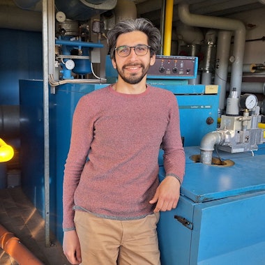 Der Energiemanager Nima Haghighatian lehnt sich mit dem Ellbogen an die Heizungsanlage der Grundschule in Dahlem.