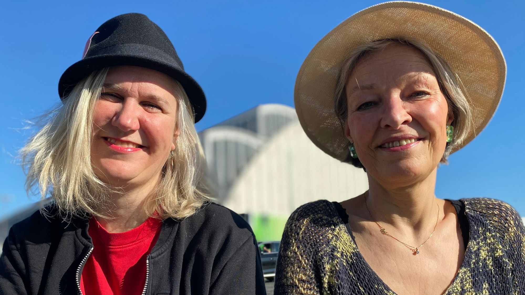 Zwei Frauen, die Hüte tragen, lachen in die Kamera