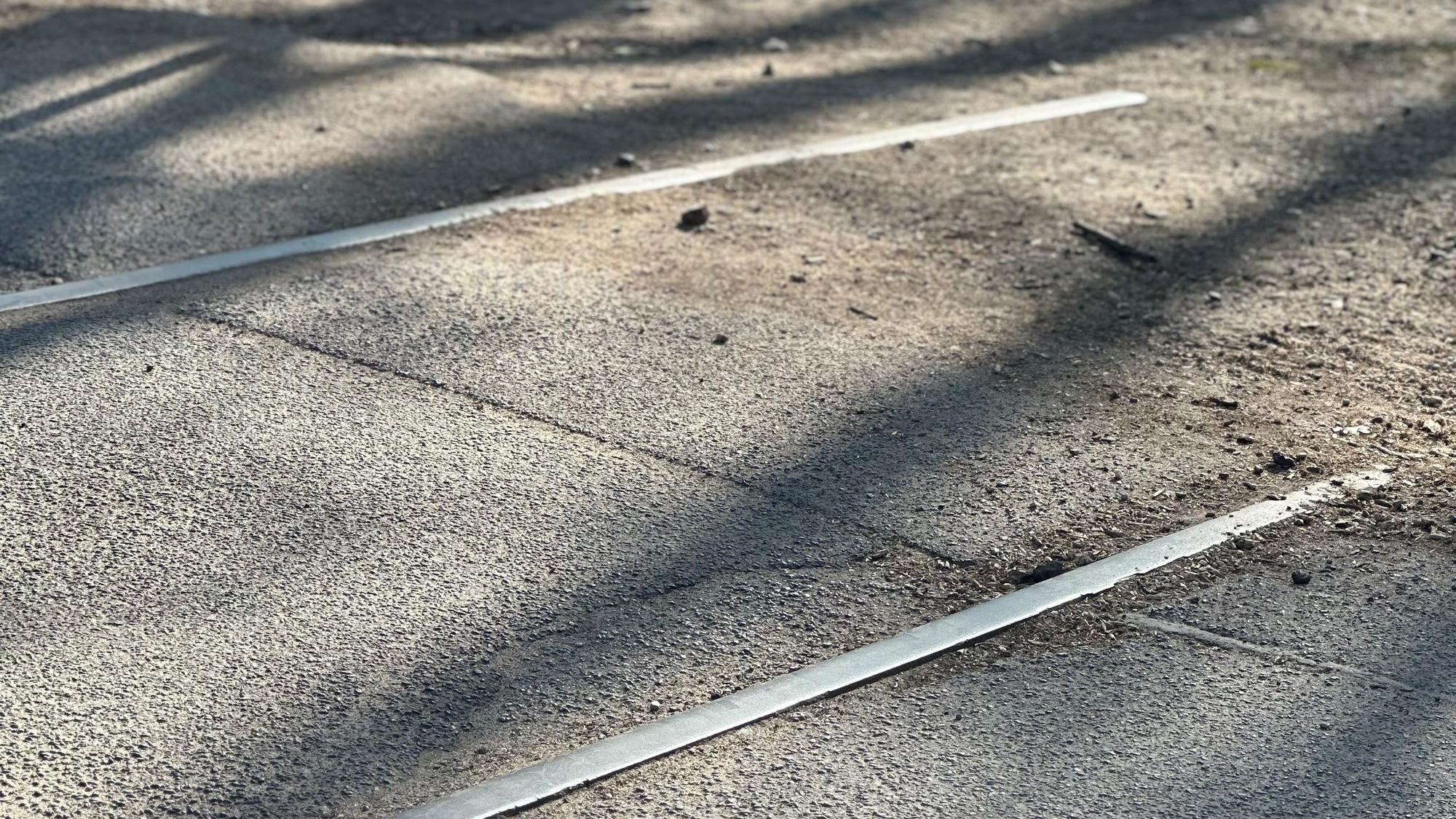 Zu sehen sind alte Schienen auf einem asphaltierten Weg.