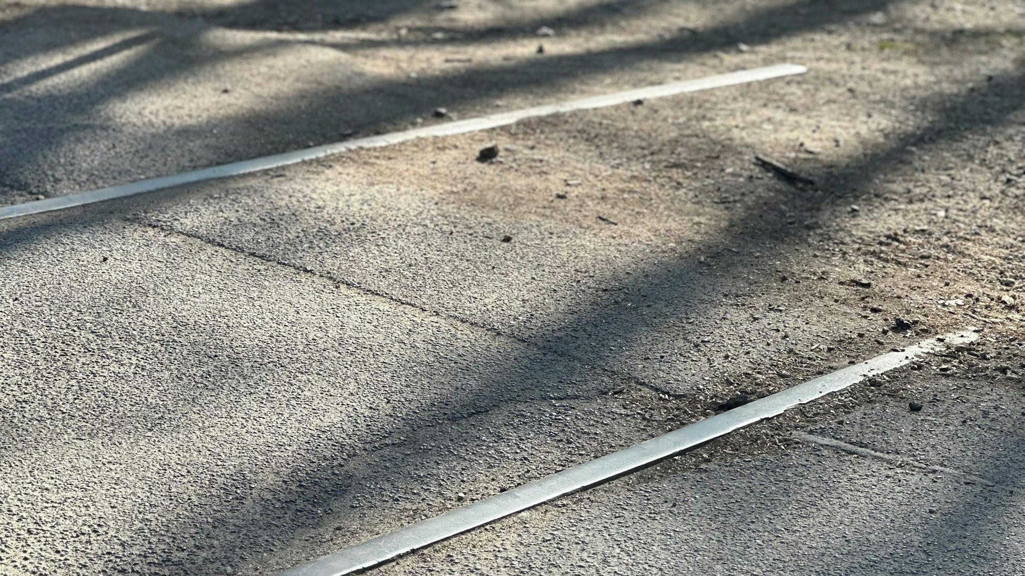 Zu sehen sind alte Schienen auf einem asphaltierten Weg.