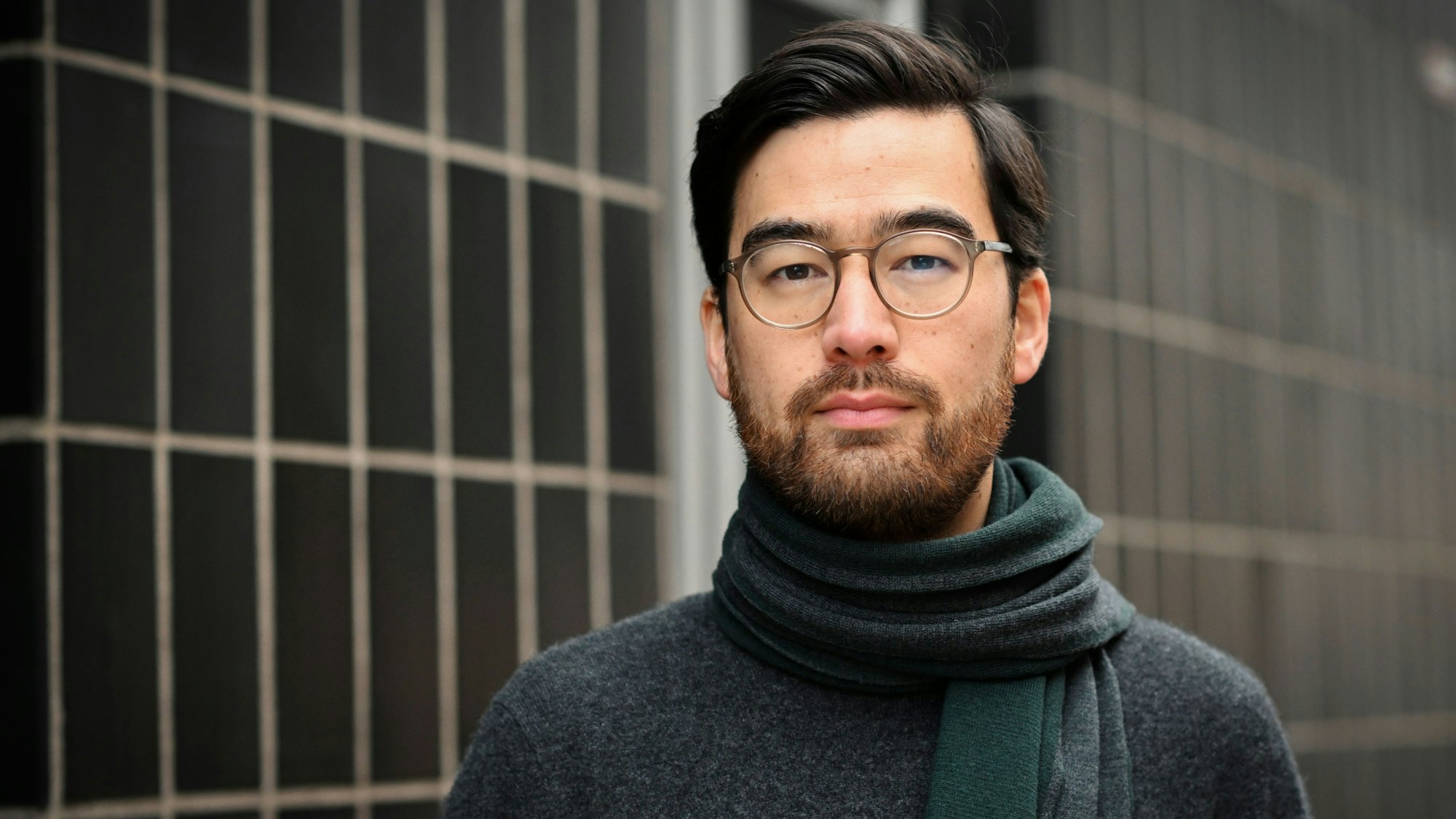 Federer steht mit Schal vor einer gekachelten Wand.