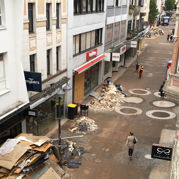 Das Bild zeigt die Neustraße, eine Passantin schaut auf Berge von Sperrmüll und Schutt.