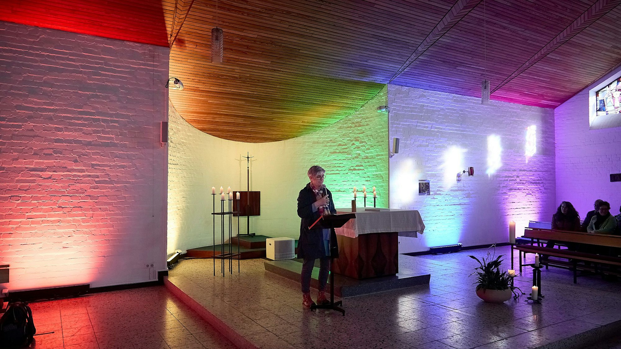 Uschi Grab steht an einem Pult in der bunt beleuchteten Kapelle in Schleiden-Scheuren.