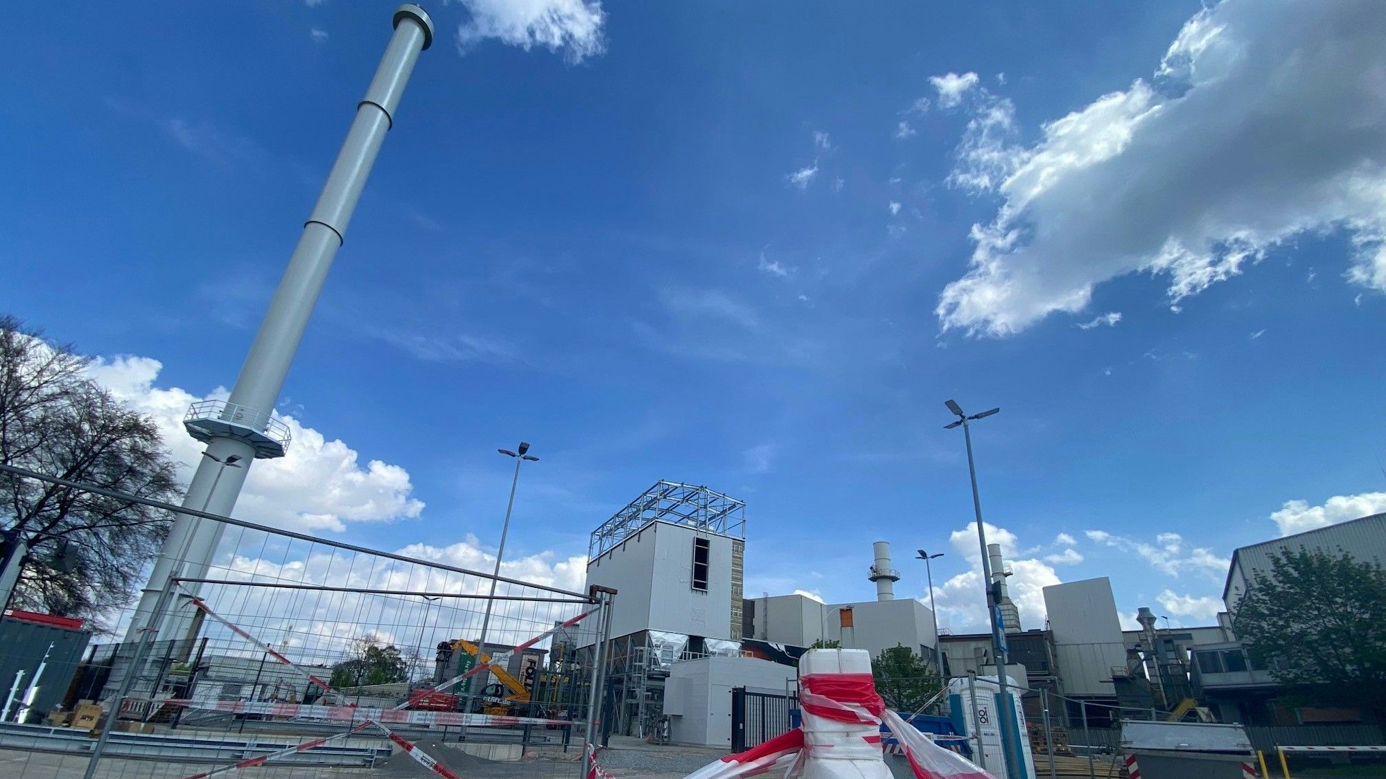 Zu sehen sind ein Schornstein und dahinter die weiteren Bauten des Eisenwerks.