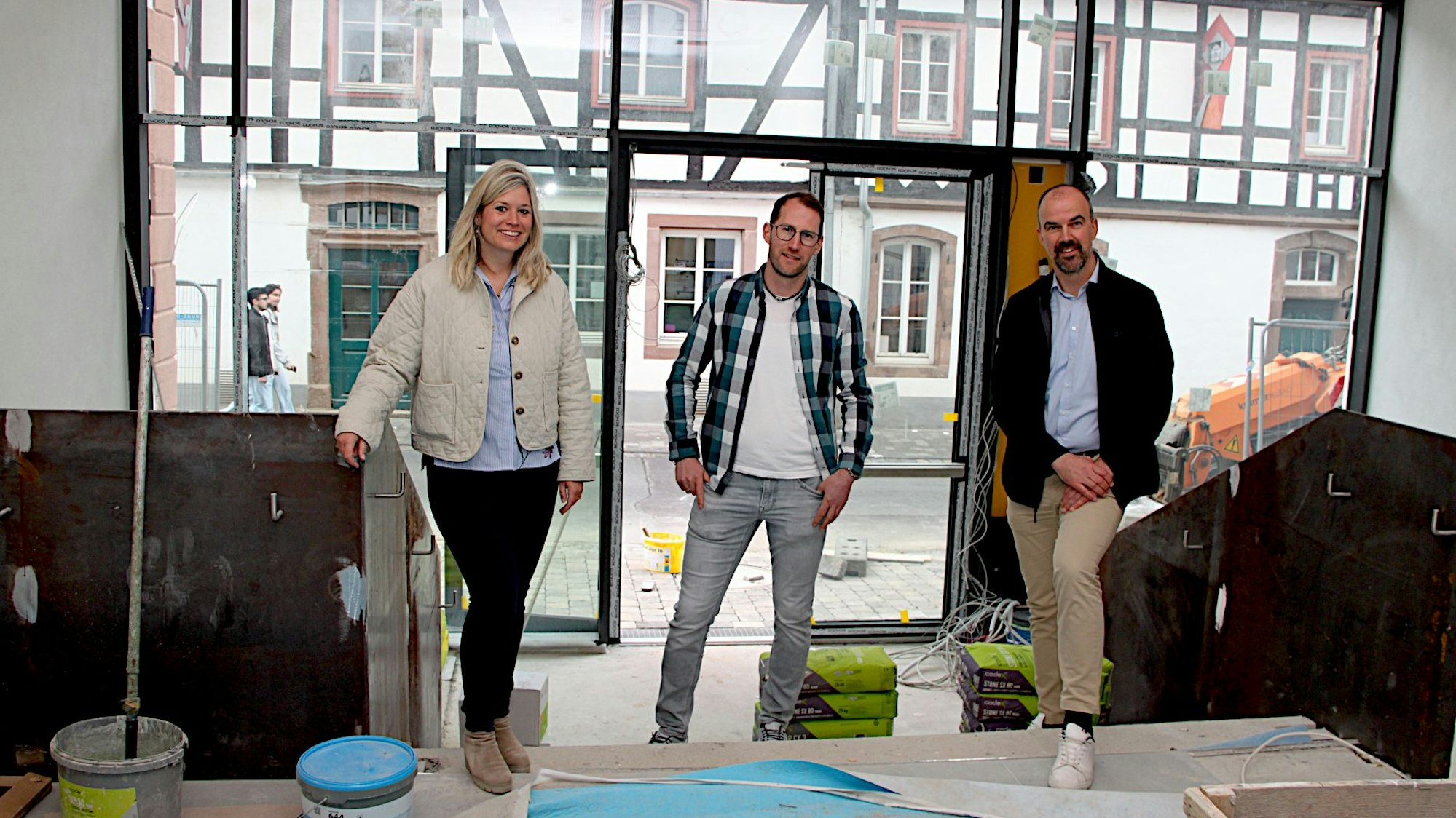 Zwei Männer und eine Frau stehen im Eingangsbereich des neuen Rathauses von Blankenheim, der noch eine Baustelle ist.