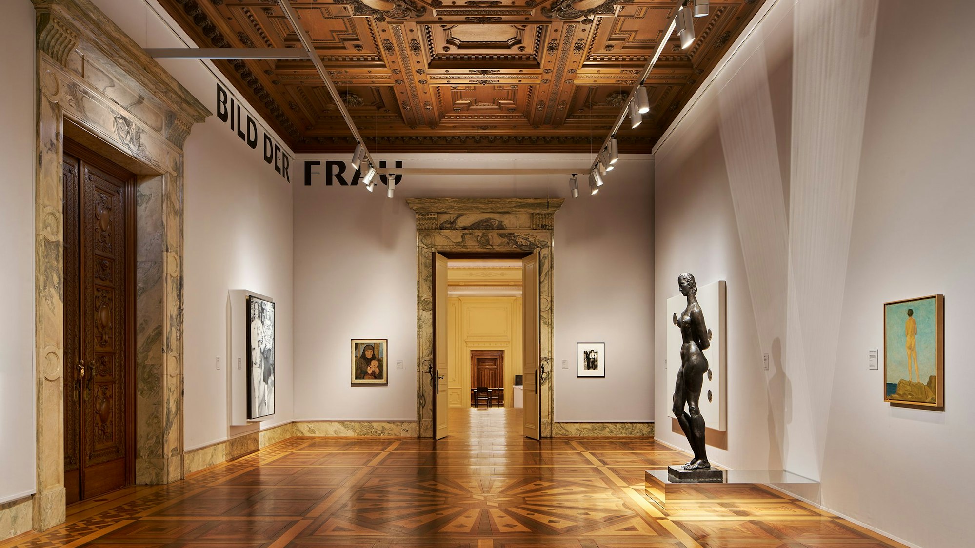 Blick in einen Ausstellungssaal mit Gemälden und Skulpturen