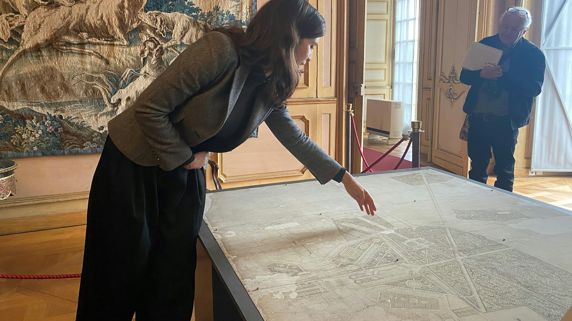 Zu sehen ist eine Frau, die auf einen Plan zeigt.