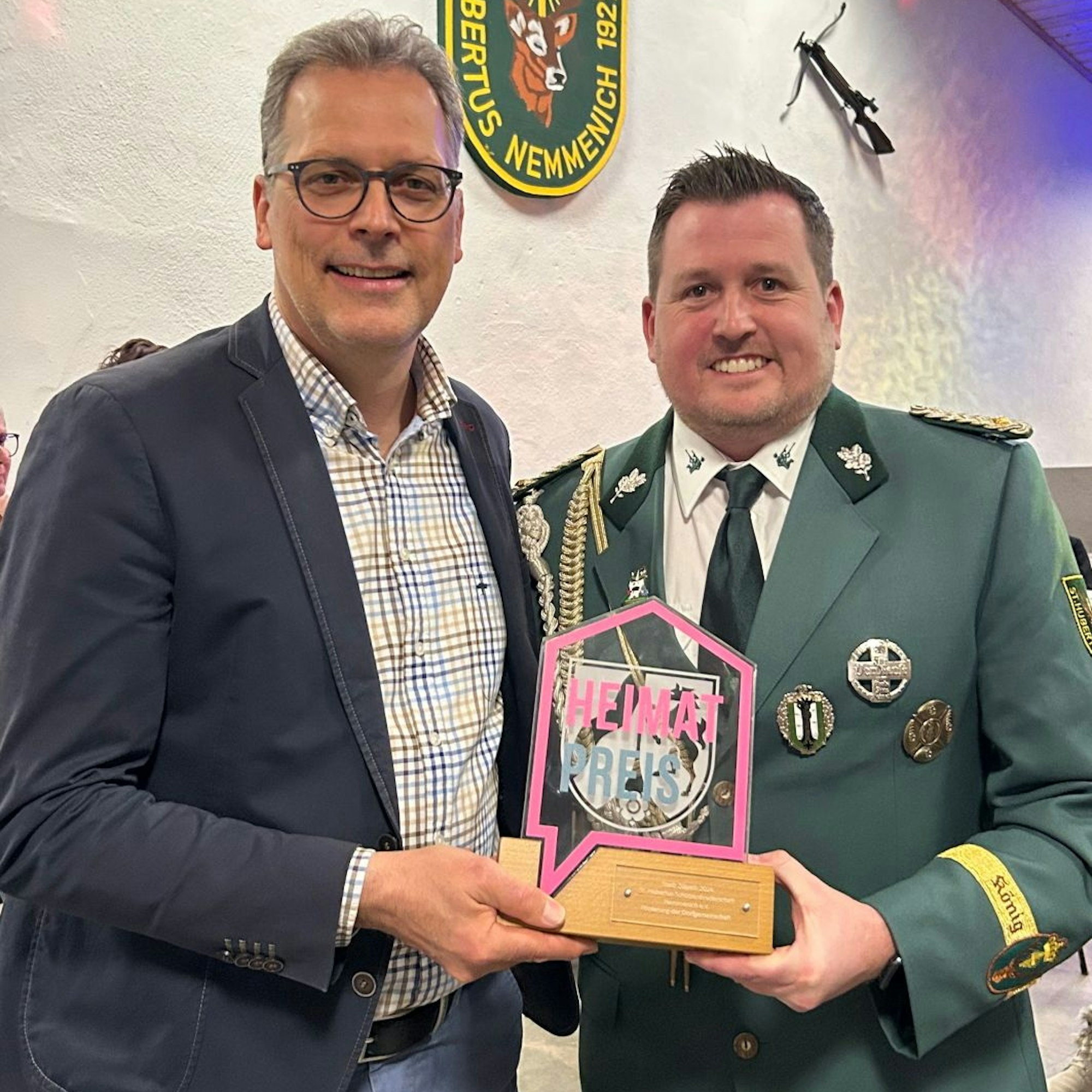 „Heimatpreis“ ist auf dem Pokal zu lesen, den Bürgermeister Ulf Hürtgen an Holger Marian überreicht.