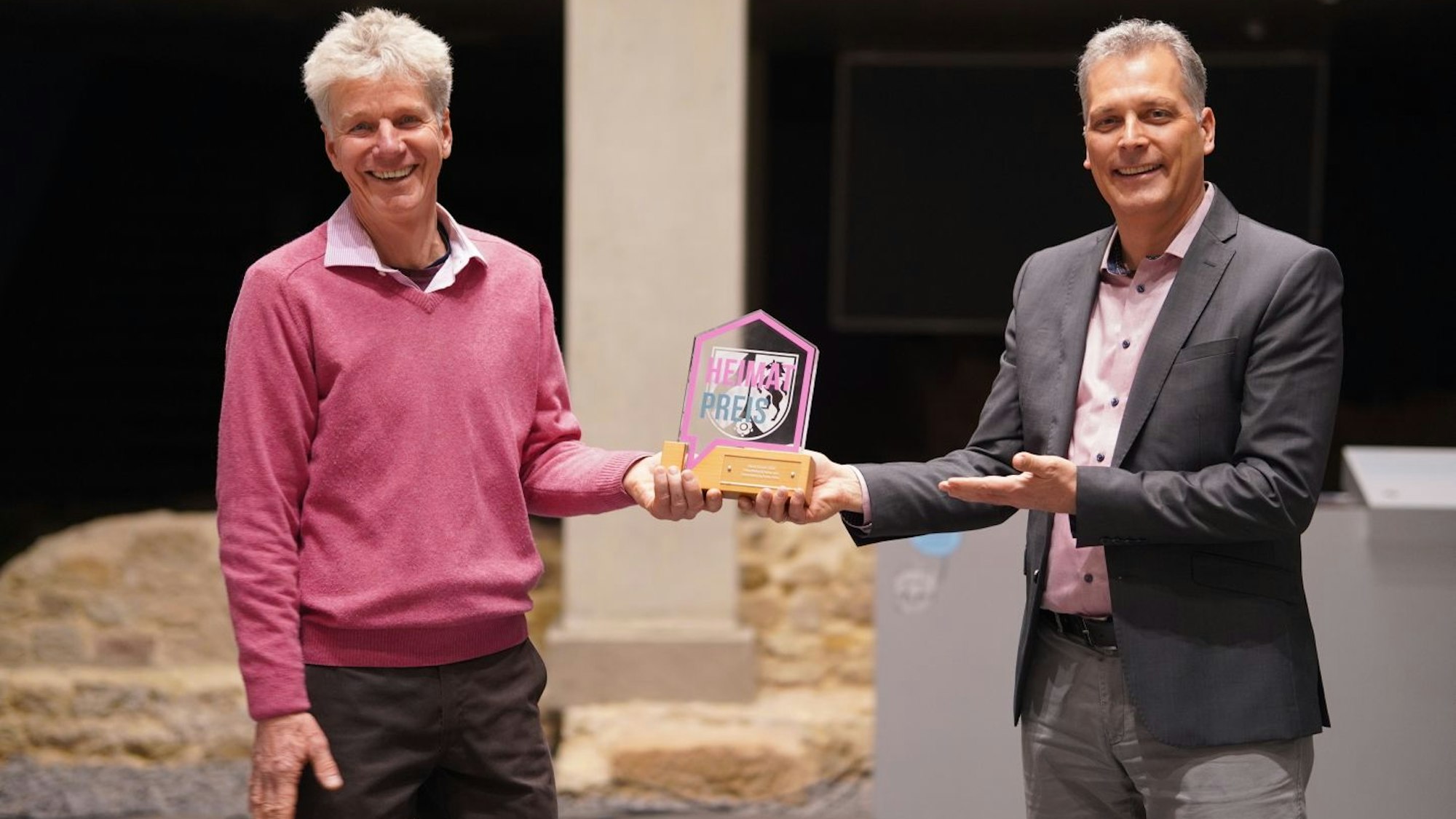 Der Zülpicher Bürgermeister überreicht Markus Eisolt einen Pokal, der aus Holz und Glas gefertigt ist.