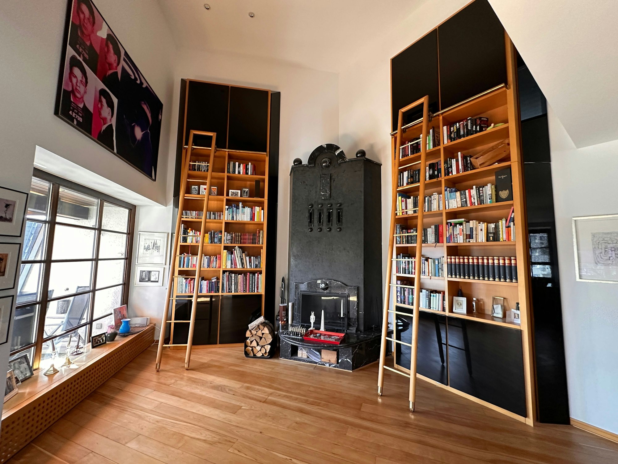 Ein Wohnraum mit einem über vier Meter hohen, schwarzen Kamin. Links und rechts vom Kamin stehen Bibliotheken, die sicherlich gute sechs Meter Höhe messen.