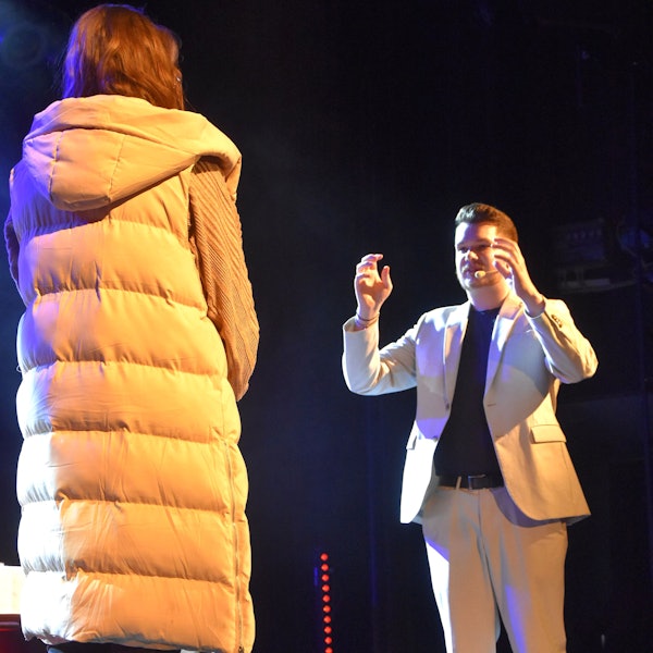 Ein Mann steht rechts von einer Frau und hält die Hnde hoch.