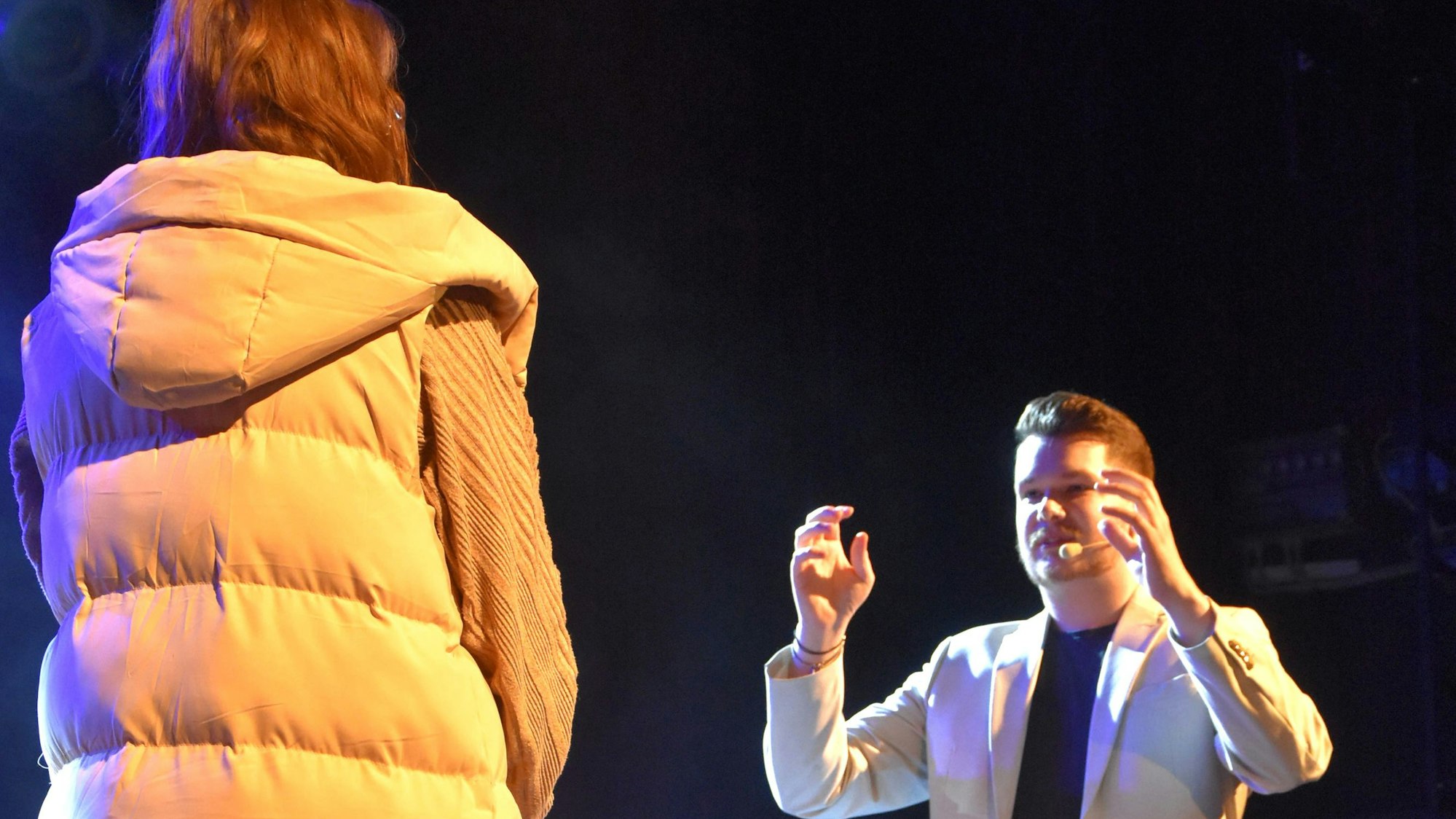 Ein Mann steht rechts von einer Frau und hält die Hnde hoch.