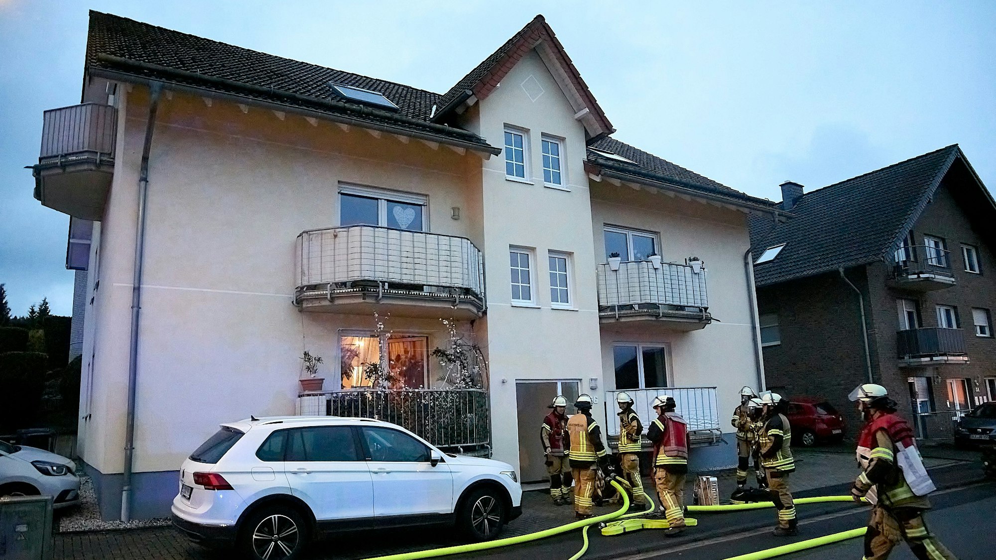 Feuerwehrleute haben vor dem Gebäude Schlauchleitungen verlegt.