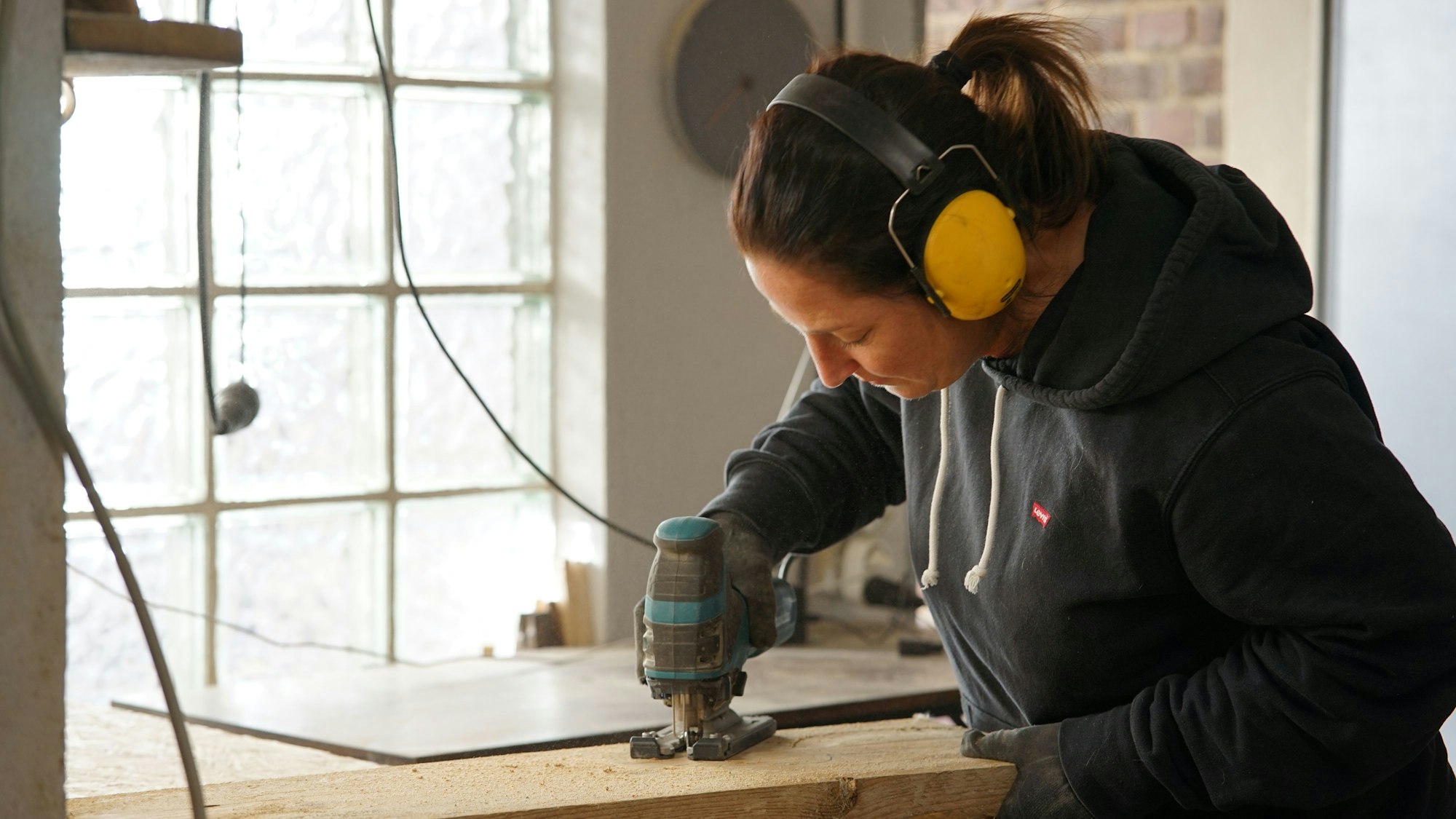 Eine Frau schneidet Holz mit einer Stichsäge.