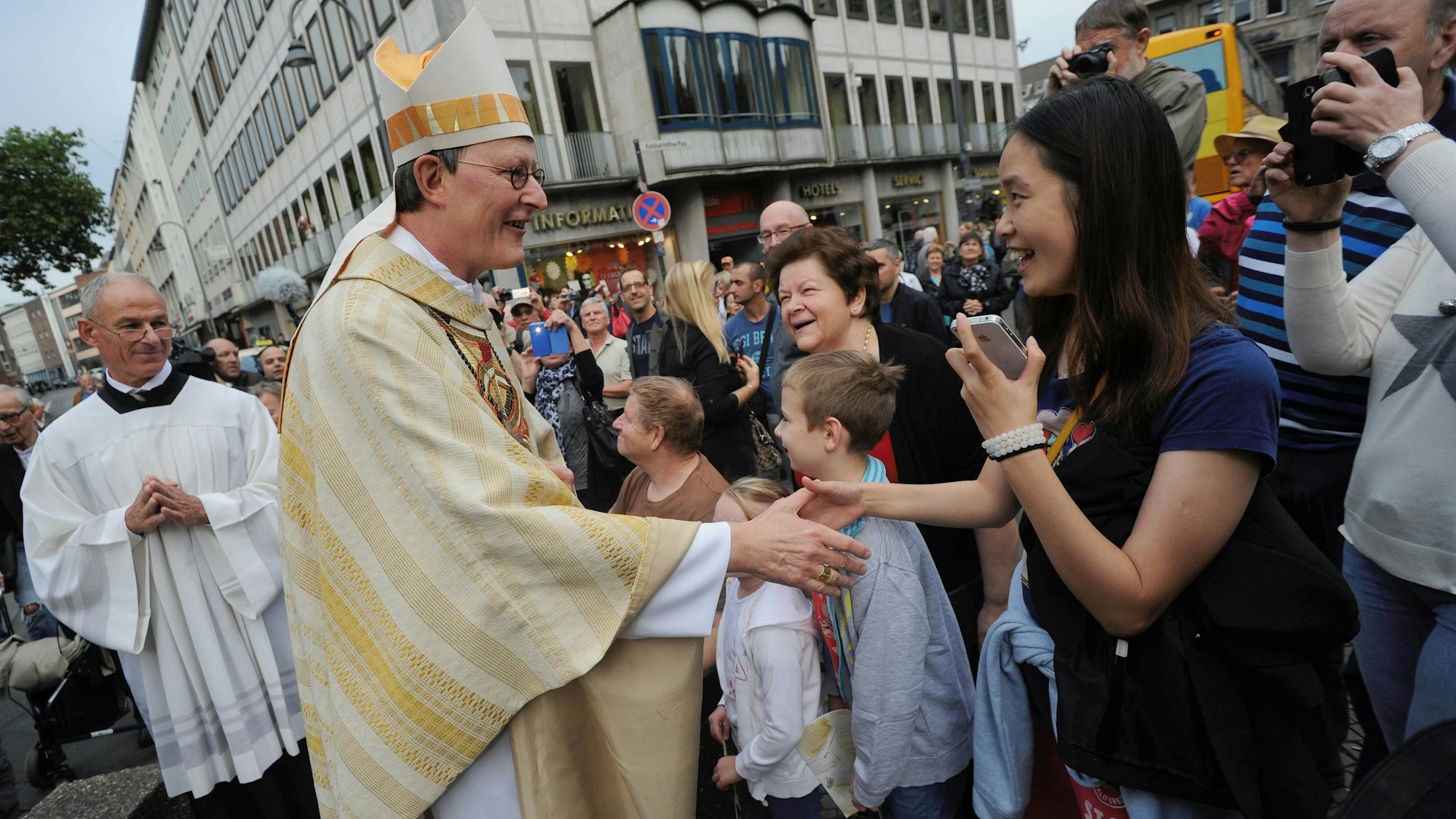 Kardinal Rainer Maria Woelki geht am 20.09.2014 in Köln (Nordrhein-Westfalen) zu einem feierlichen Gottesdienst zu seiner Amtseinführung als neuer Kölner Erzbischof und begrüßt Passanten.