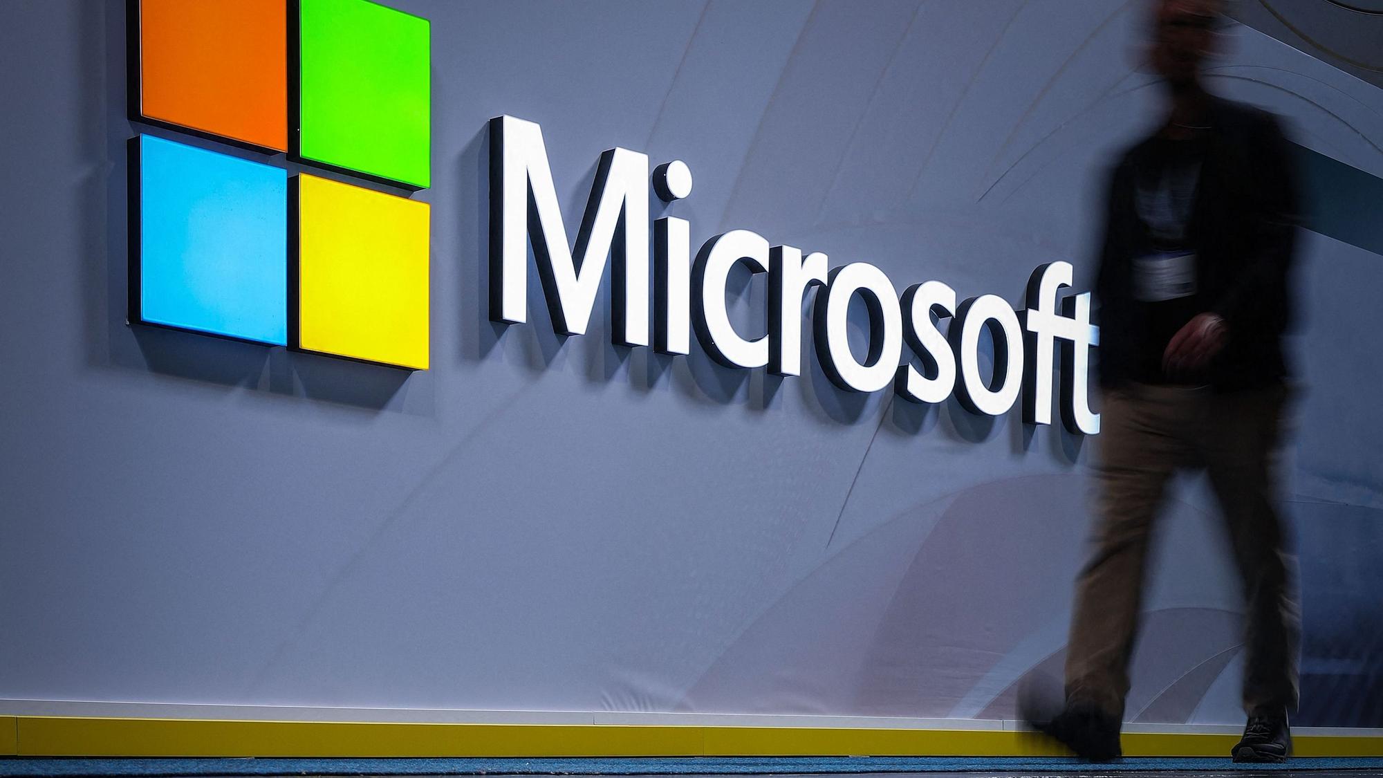 Ein Mann geht an einem Logo mit der Aufschrift Microsoft vorbei.