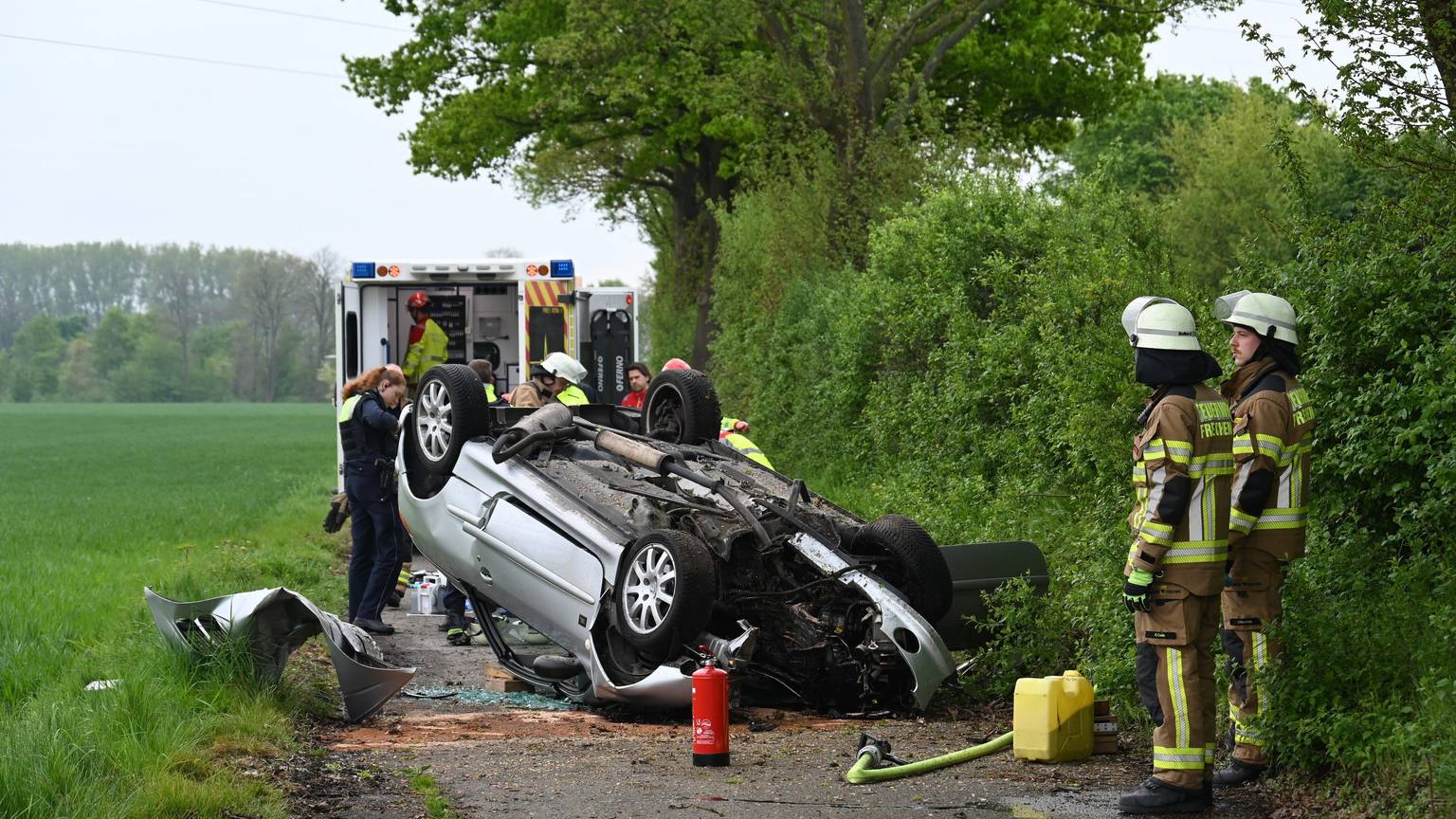 Das Bild zeigt einen Wagen, der auf dem Dach liegt und mehrere Einsatzkräfte.