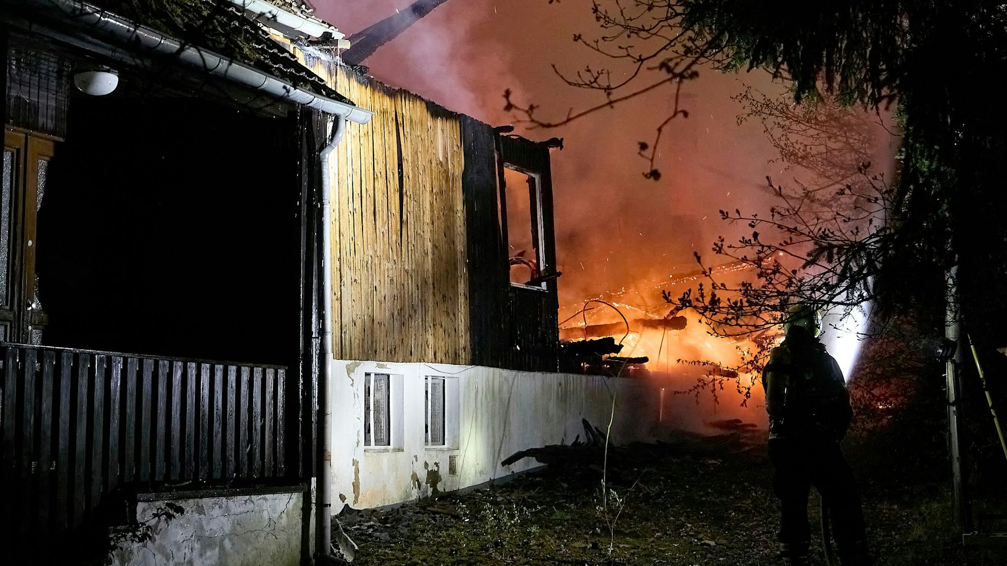 Ein Feuerwehrmann schaut in der Dunkelheit auf die sich ausdehnenden Flammen.