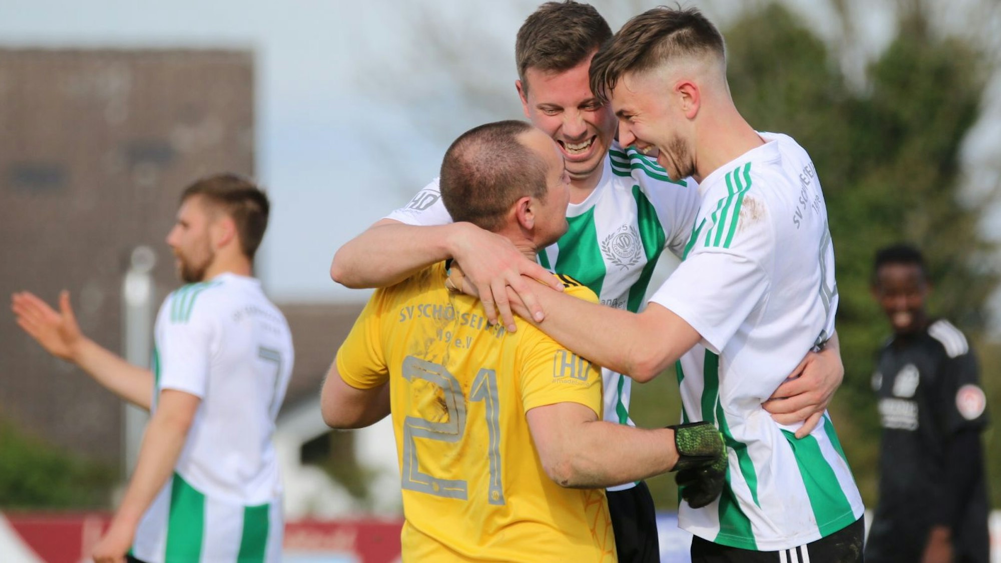 Drei Spieler des SV Schöneseiffen liegen sich in den Armen und jubeln.