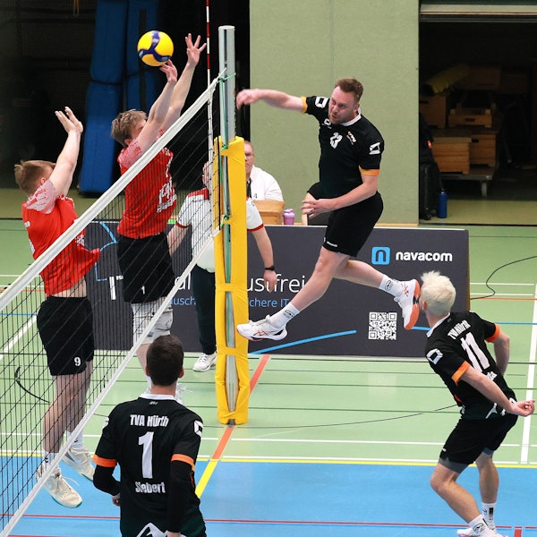 Das Foto zeigt einen Hürther Volleyballer im schwarzen Trikot, der den Ball über das Netz schmettert.