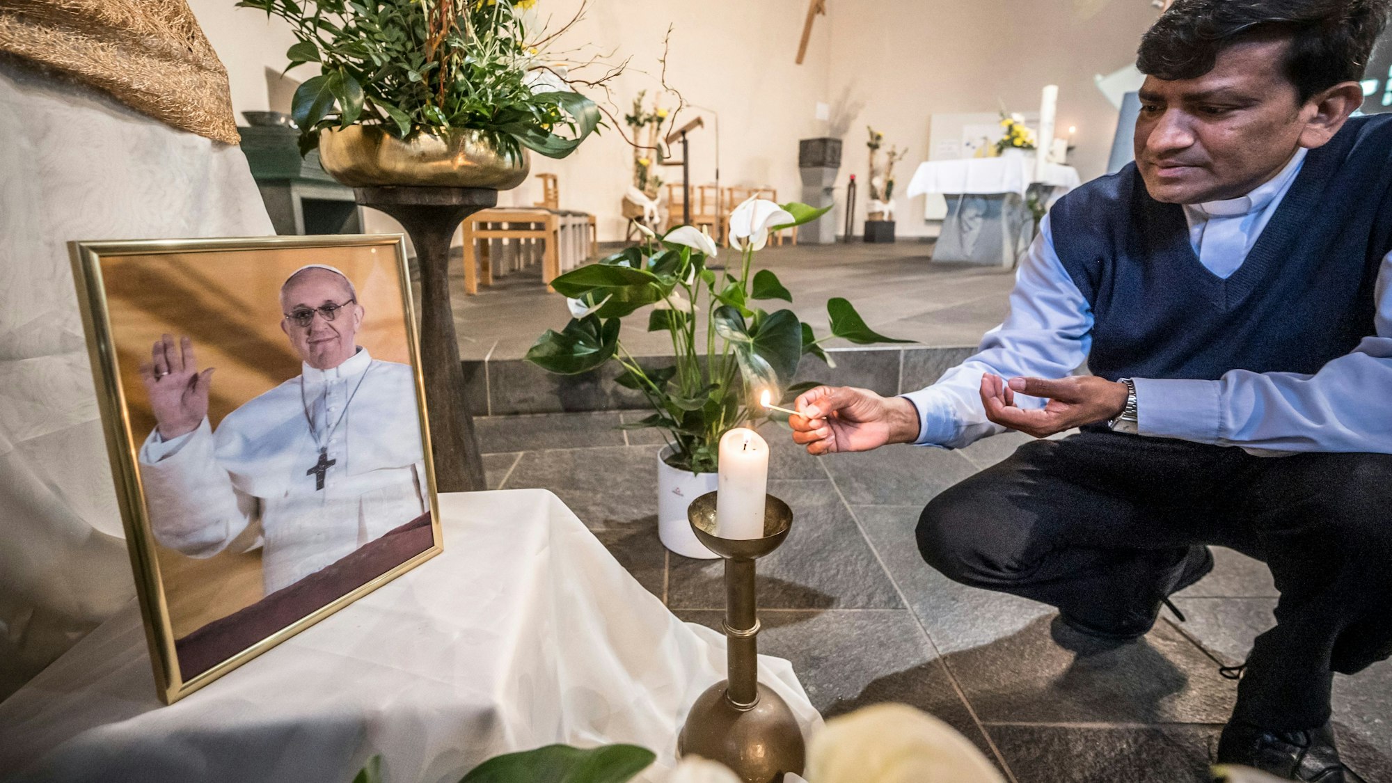 Papst Franziskus ist am Morgen des Ostermontag 2025 gestorben. Pfarrer Andrew Godugunuru stellt ein Bild in der Kirche Sankt Kildegard in Wiesdorf auf. Bild: Ralf krieger
