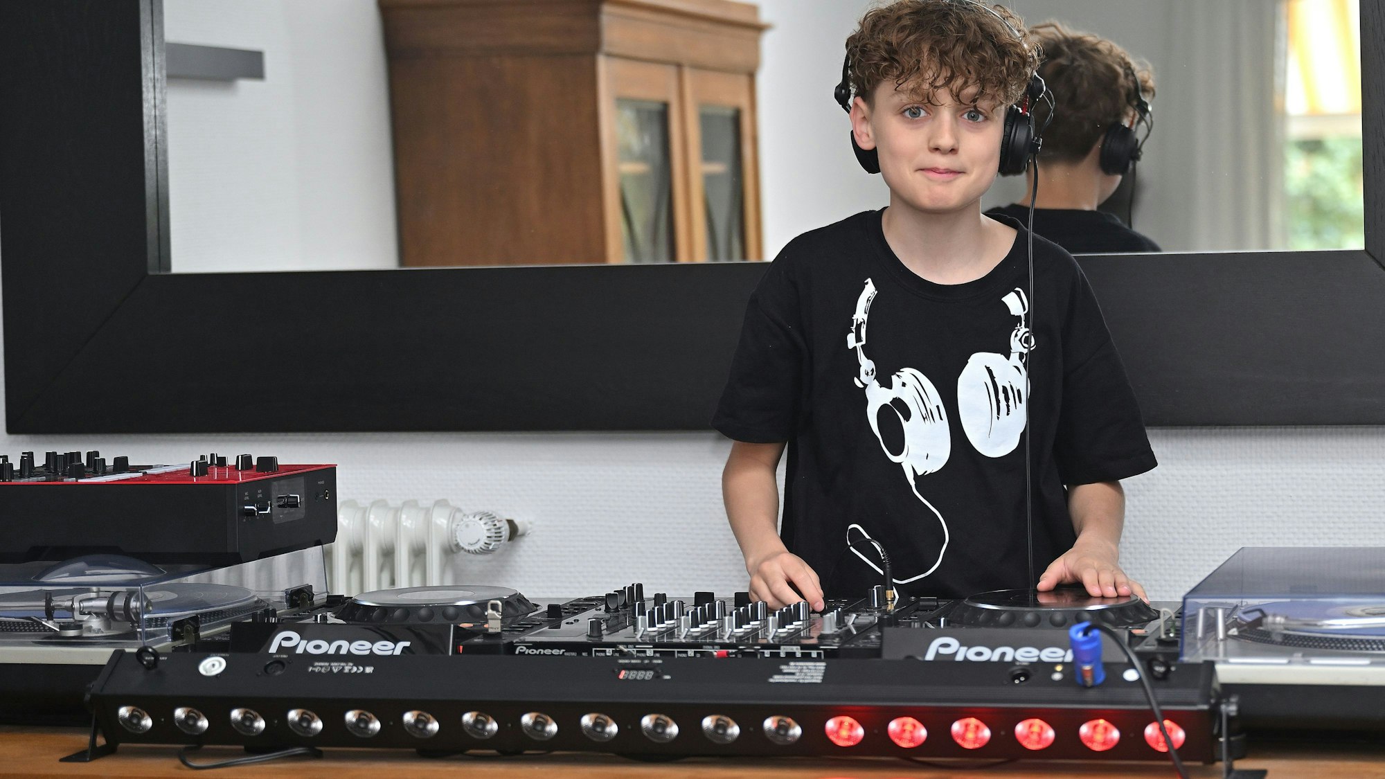 Ein 12 Jahre alter Junge steht hinter einem Mischpult für elektronische Musik.
