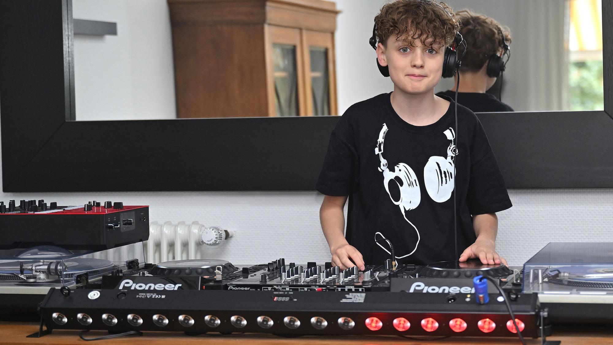 Ein 12 Jahre alter Junge steht hinter einem Mischpult für elektronische Musik.