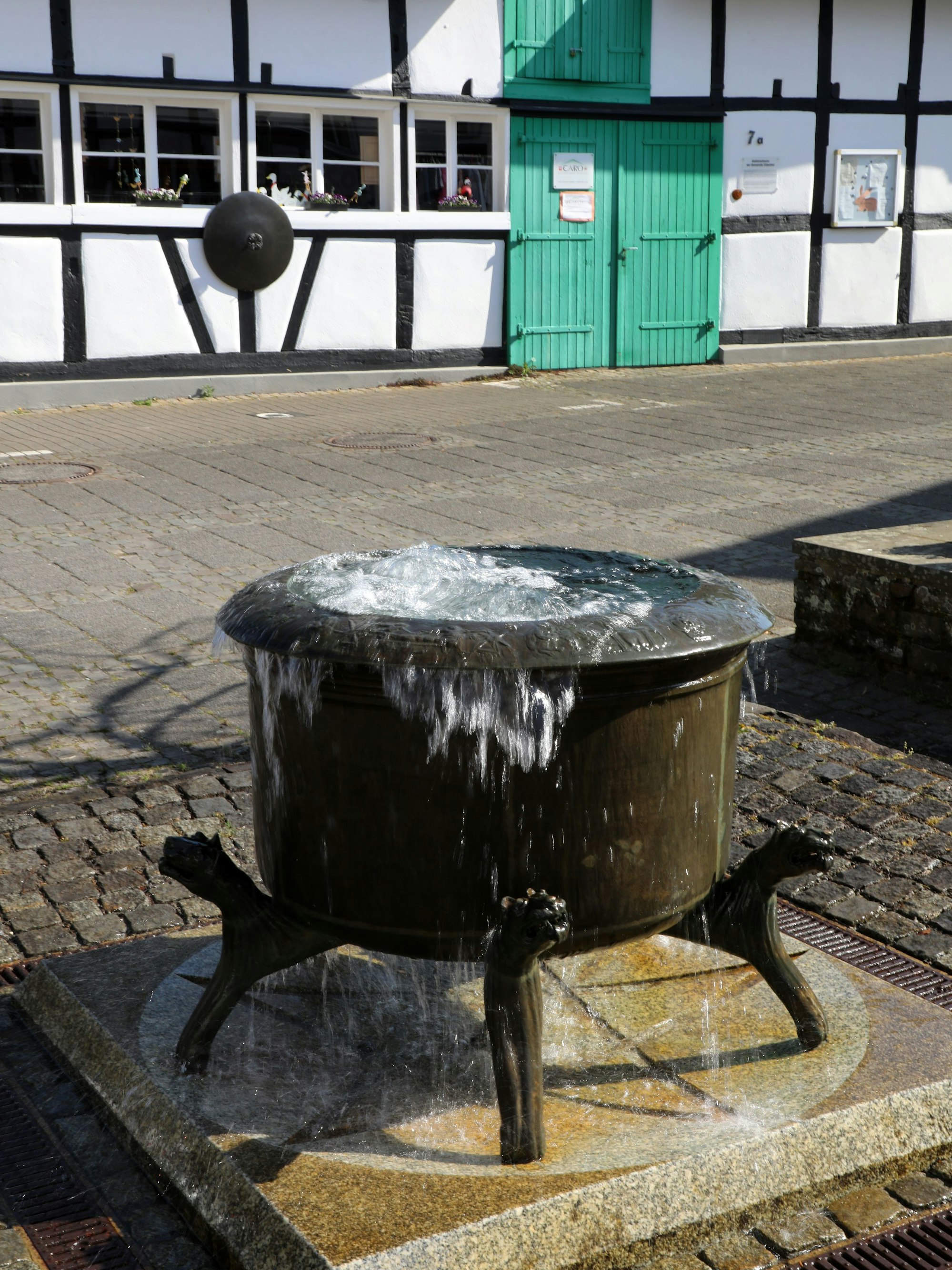 Der Odenthaler Hexenbrunnen sprudelt auf dem Dorfplatz vor der Odenthaler Künstlerscheune.
