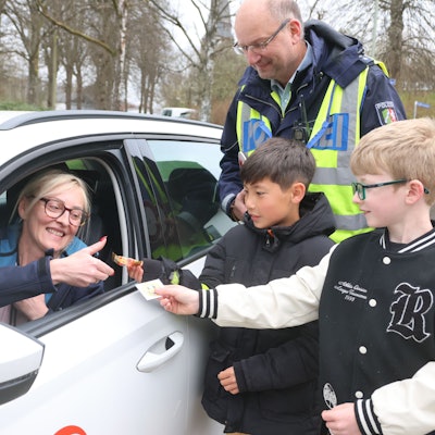 Begleitet von Markus Klein bedanken sich die beiden Zehnjährigen Tom und Noah bei einer Waldbrölerin für ihre vorsichtige Fahrweise.