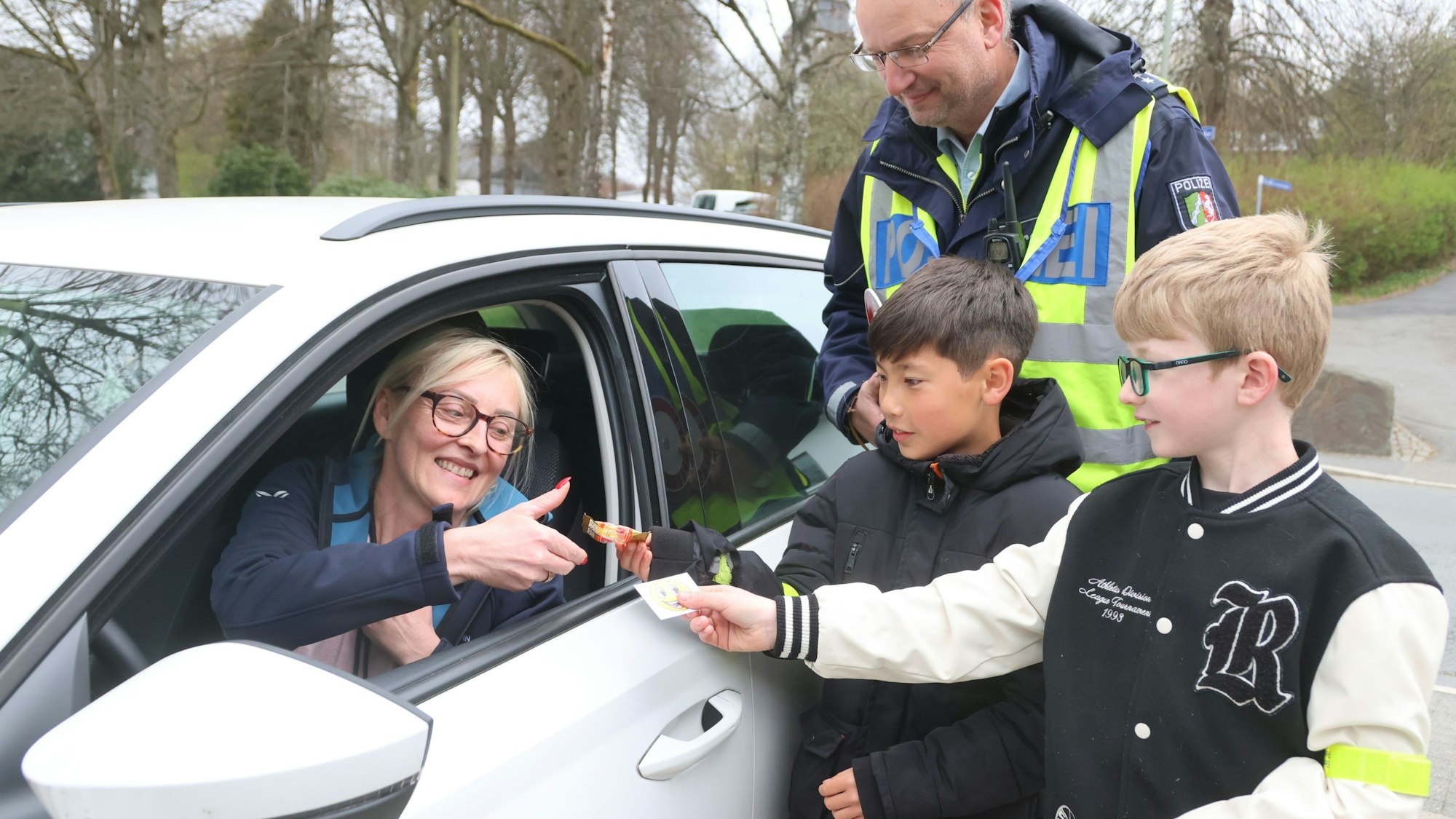 Begleitet von Markus Klein bedanken sich die beiden Zehnjährigen Tom und Noah bei einer Waldbrölerin für ihre vorsichtige Fahrweise.