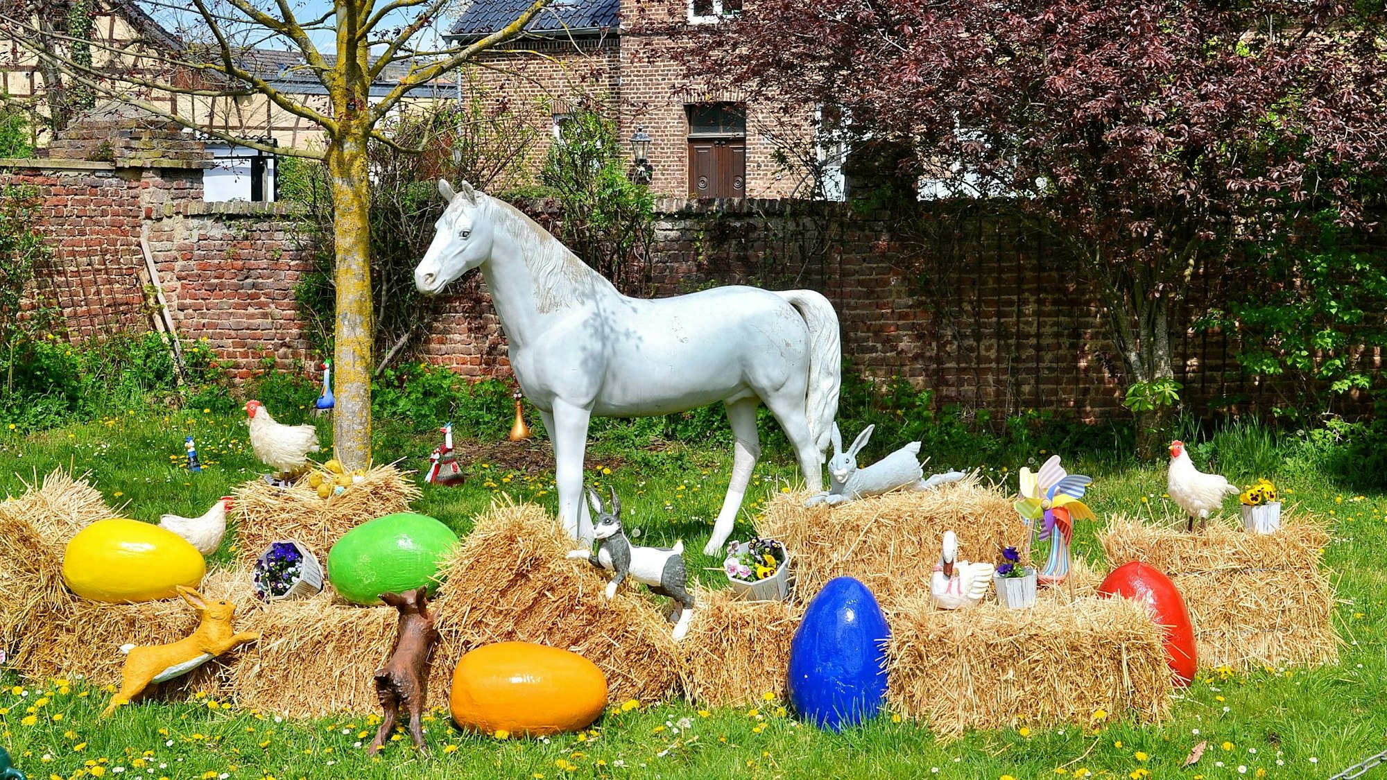 An einem Kreis aus Strohballen sind überdimensionale Ostereier sowie Attrappen von Hühnern und ein großes weißes Plastikpferd aufgestellt.