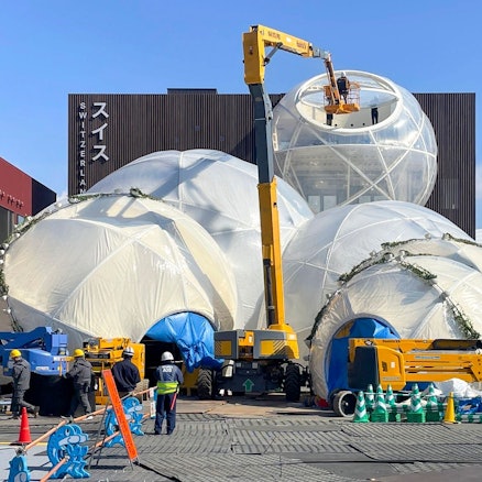 Zu sehen ist ein Pavillon, vor dem ein Kran steht.