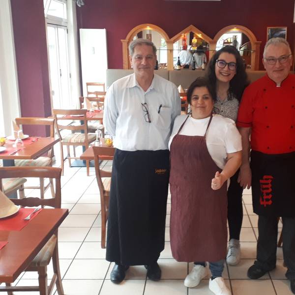 Zwei Männer und eine Frau stehen im Gastraum eines Restaurants.