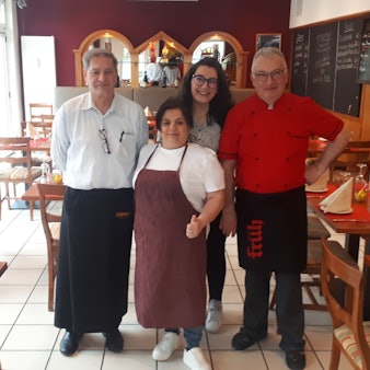 Zwei Männer und eine Frau stehen im Gastraum eines Restaurants.