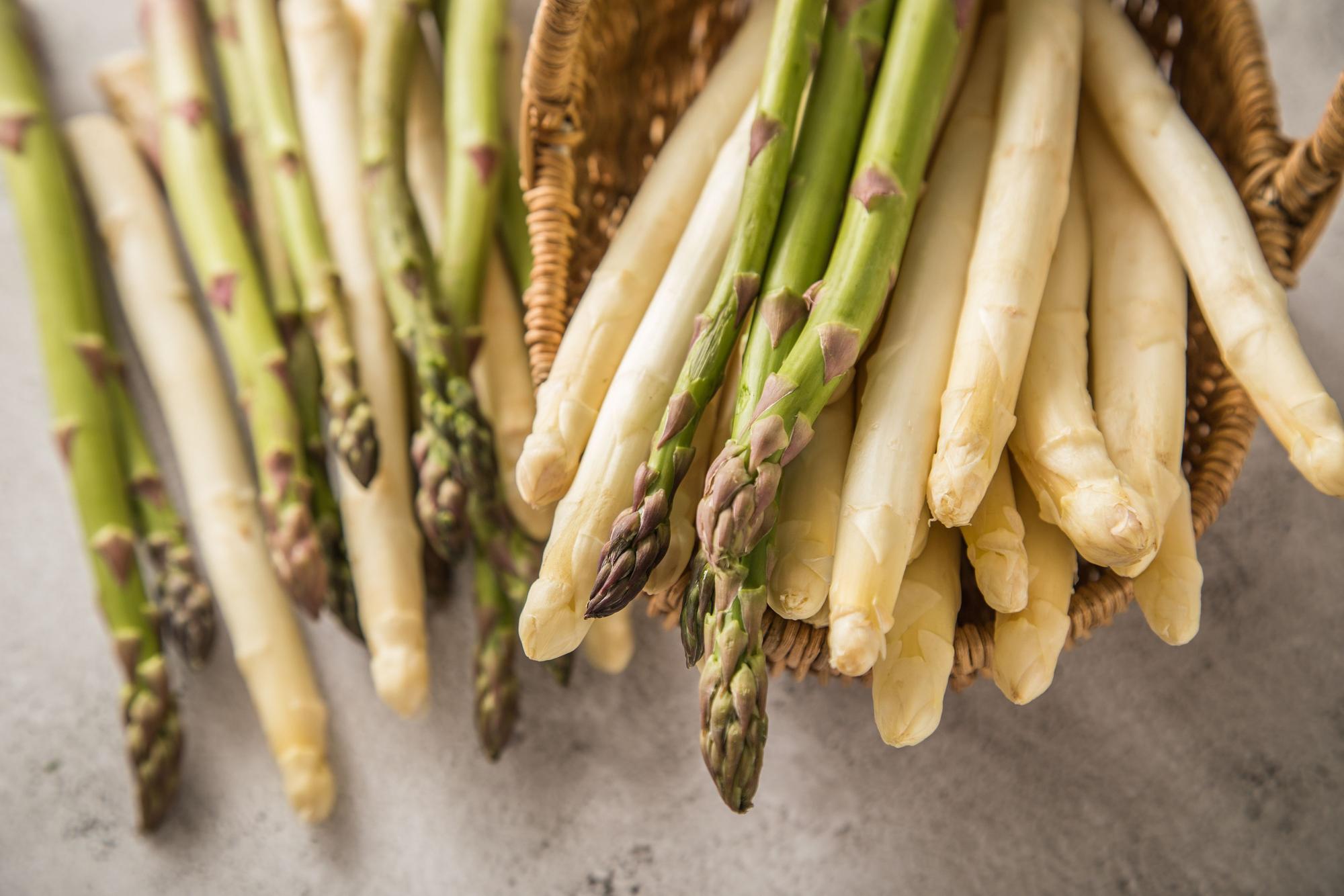 Weißer und grüner Spargel in und an einem Weidekorb.