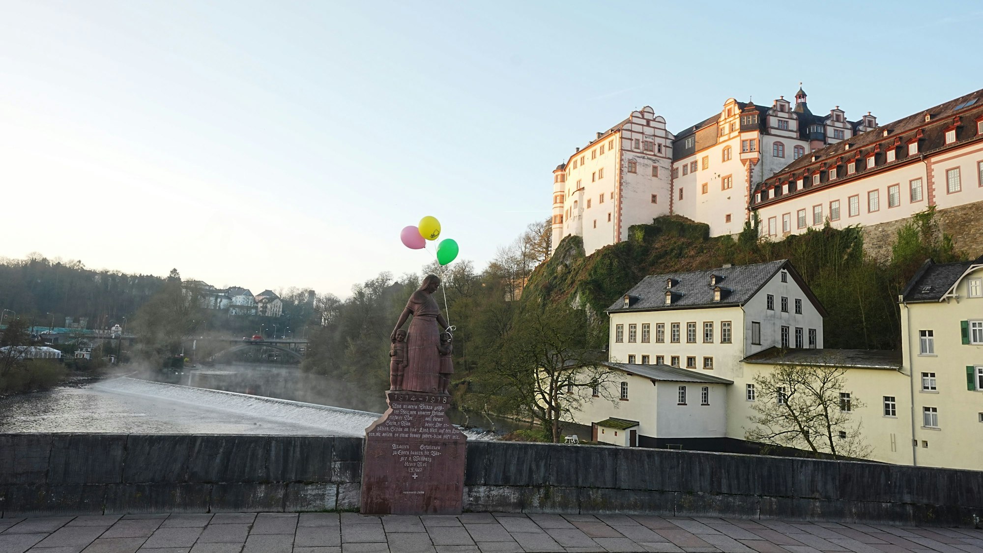 In Weilburg sind an vielen Orten, auch am Denkmal auf der Steinernen Brücke, das die Mutterfigur mit zwei Kindern zeigt, Luftballons angebracht.