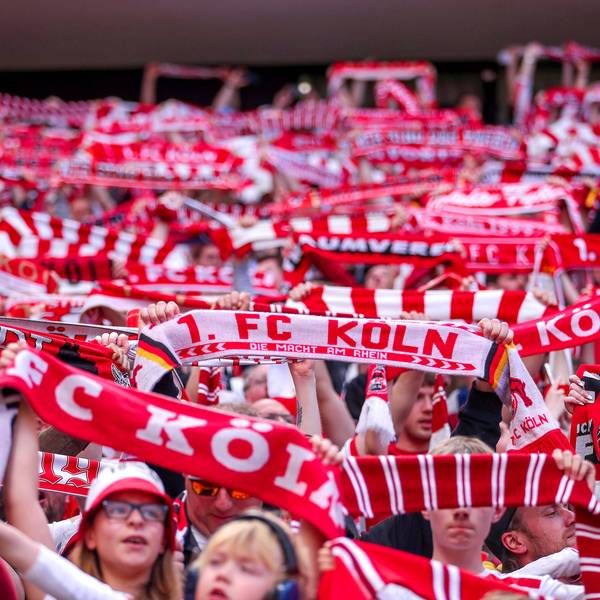 Fans vom FC köln singen die Hymne und halten Schals in die Höhe.