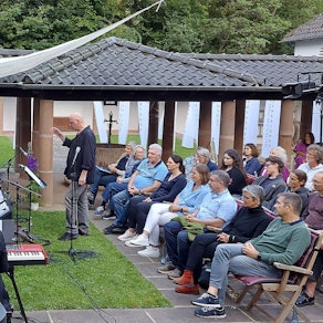 Das Orchester spielt im Freien vor einer sitzenden Menschenmenge.