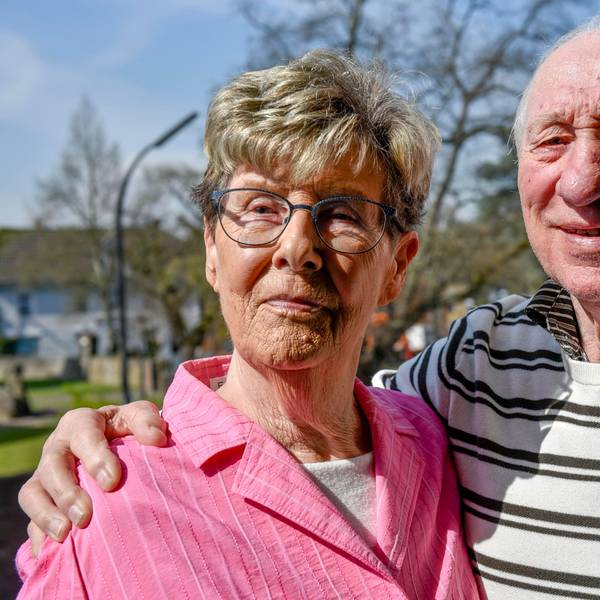 Ein älteres Ehepaar steht in der Sonne und lächelt.