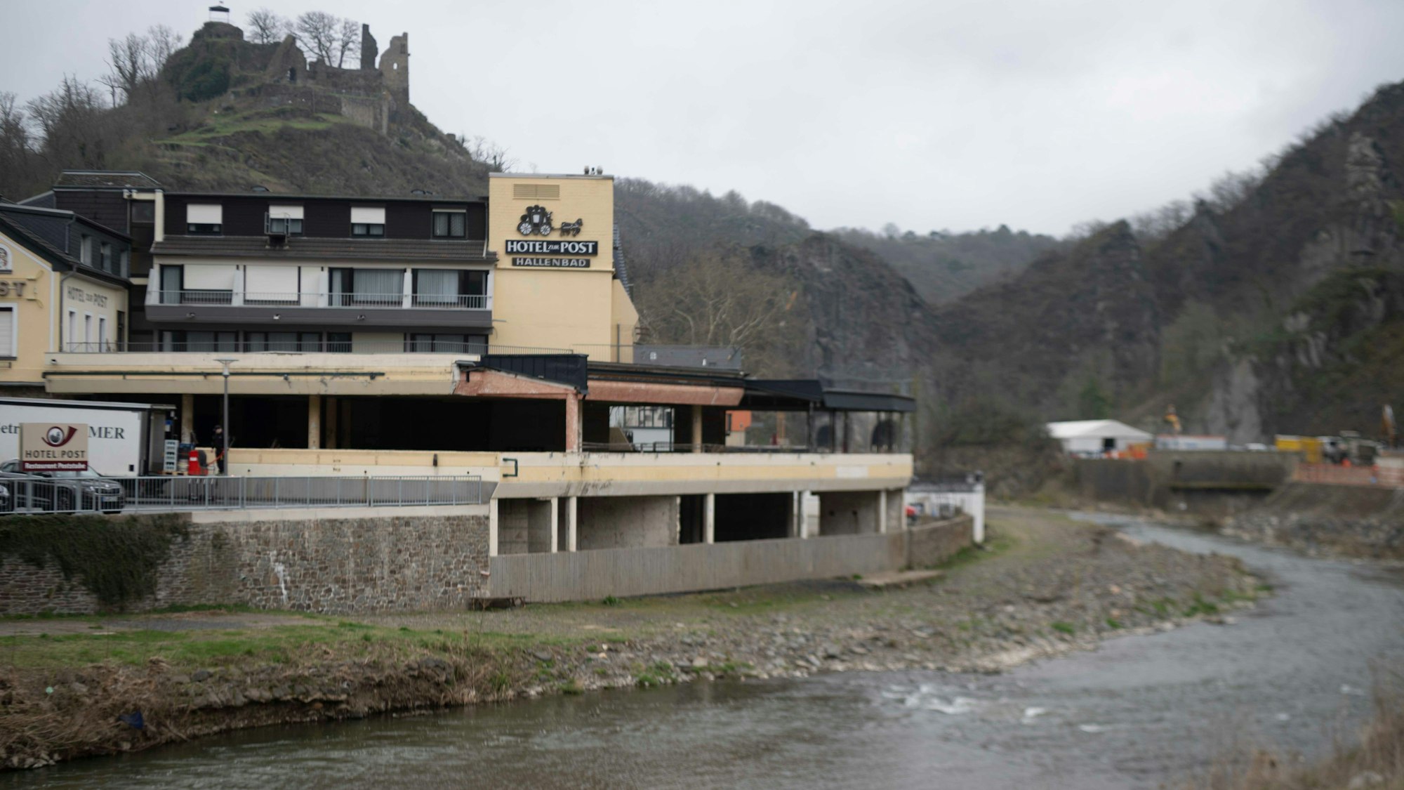 Blick auf ein leerstehendes Restaurant im Ahrtal, darüber eine Burgruine.