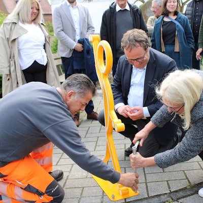 Verkehrsminister Oliver Krischer und Bürgermeisterin Claudia Wieja bringen einen Aufsteller für mehr Sicherheit am Knoten Bachstraße/ Rathausstraße/ Am Bungert an.
