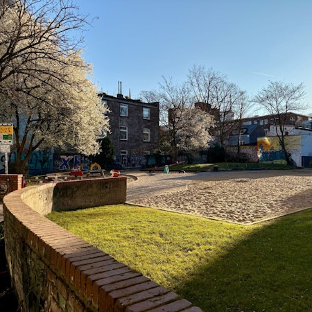 Ein riesiger leerer Sandkasten macht die größte Fläche eines Spielplatzes aus.