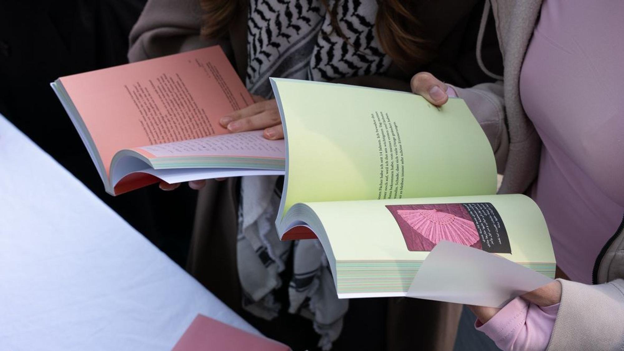 Zu sehen sind die Hände zweier Personen, die Bücher in ihren Händen halten.