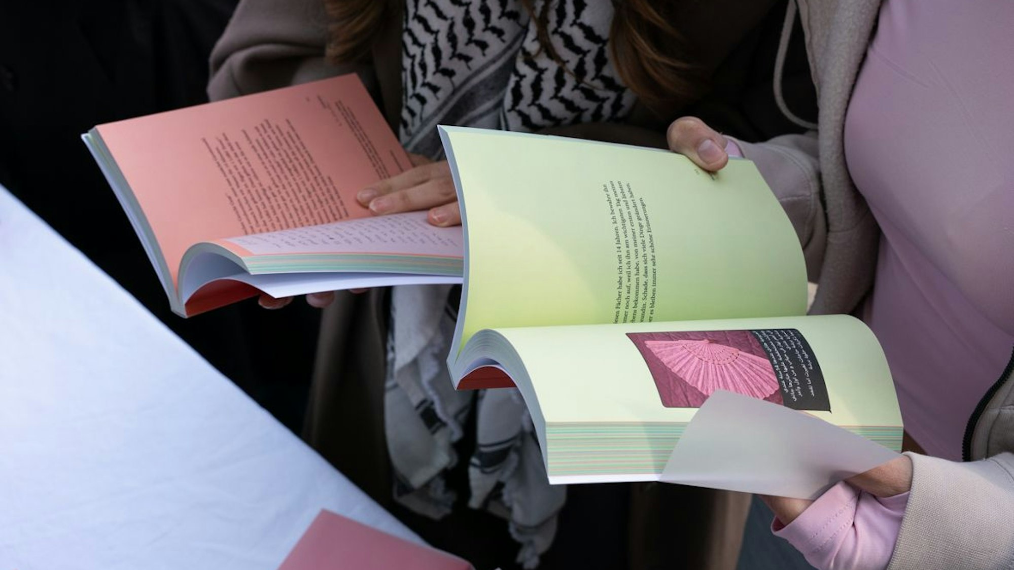 Zu sehen sind die Hände zweier Personen, die Bücher in ihren Händen halten.